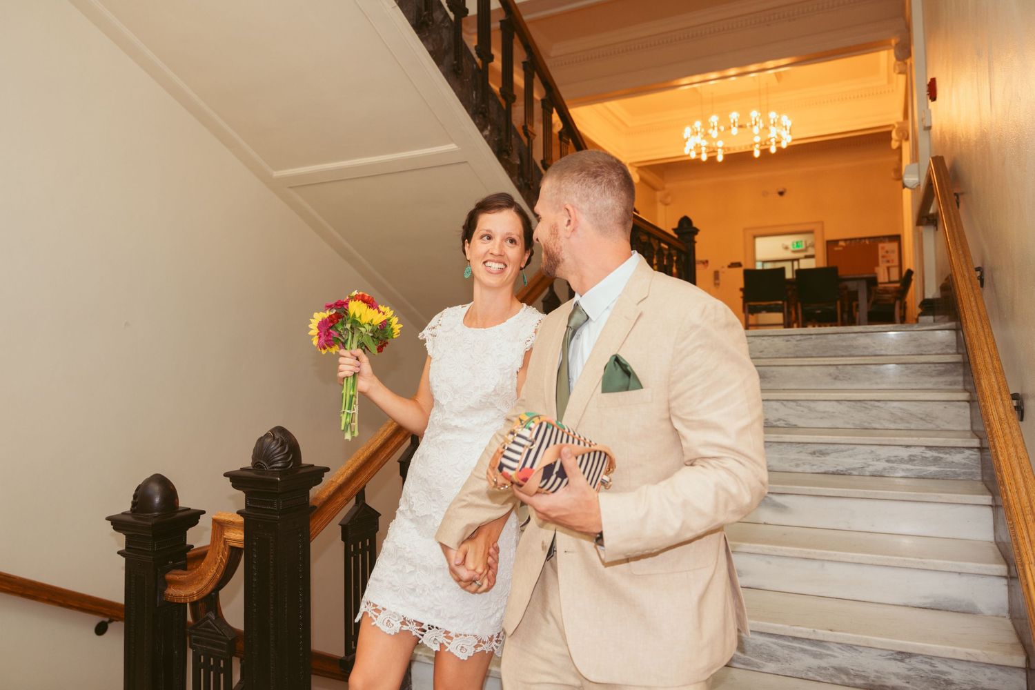 A couple descends a grand staircase with a checkered floor pattern.