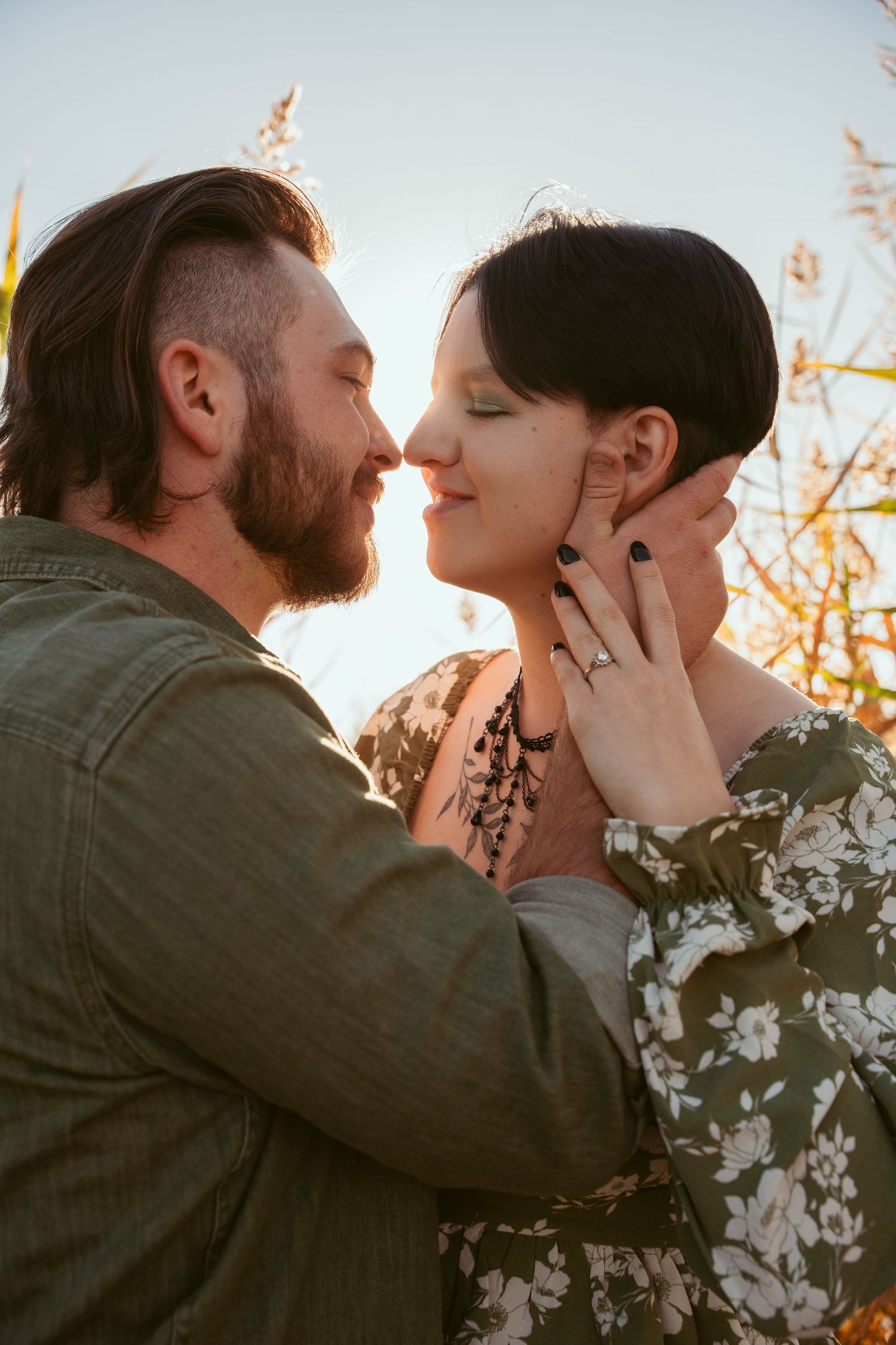 Intimate moment between couple against sunset backdrop with one wearing floral print.