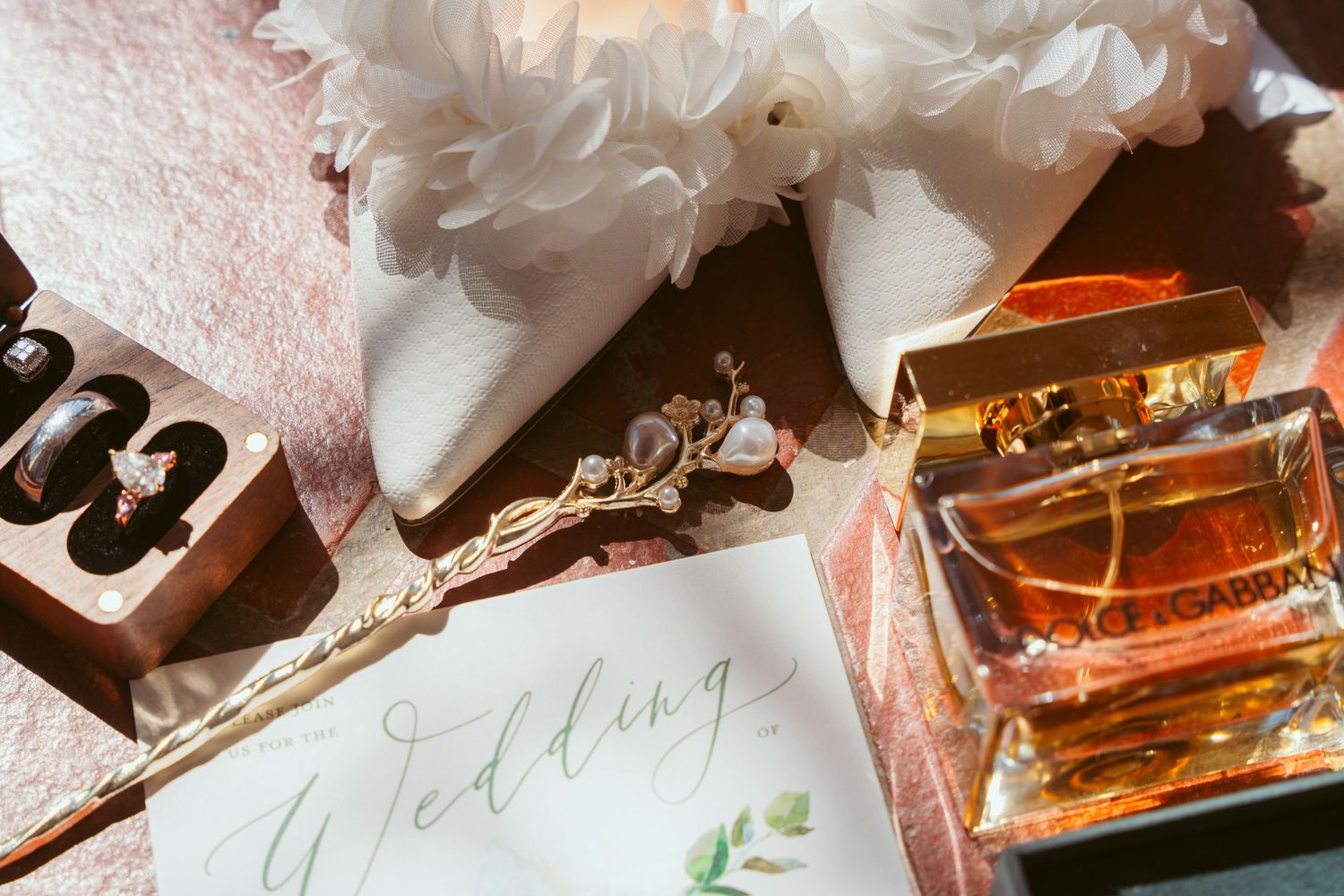Wedding details featuring elegant calligraphy and amber-colored glass bottles on a textured surface.