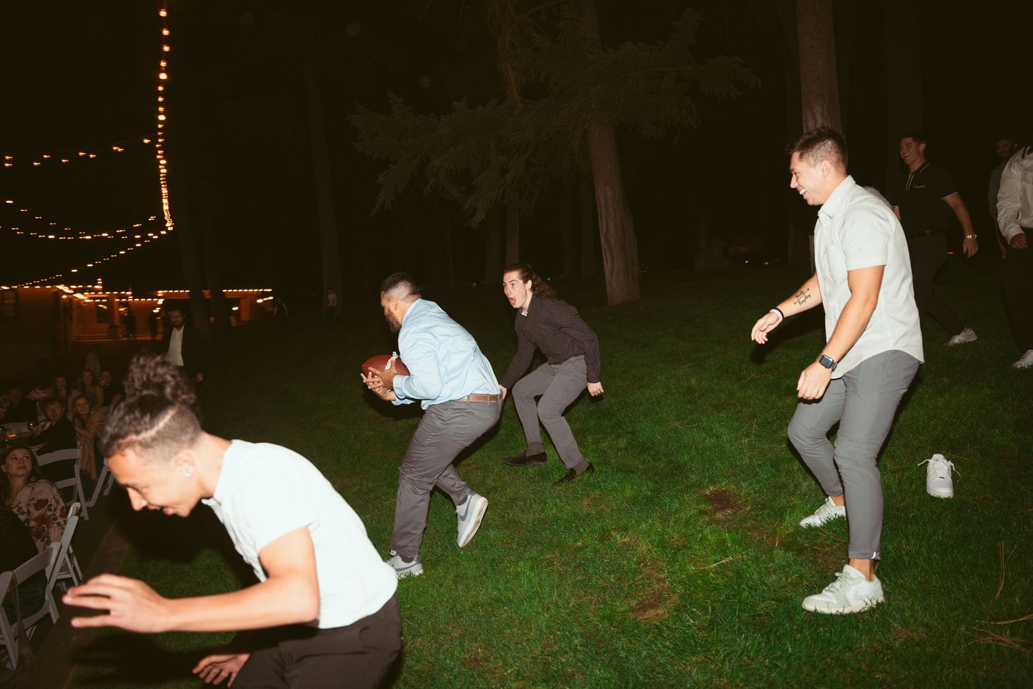 People dancing energetically on an outdoor dance floor at night under string lights.
