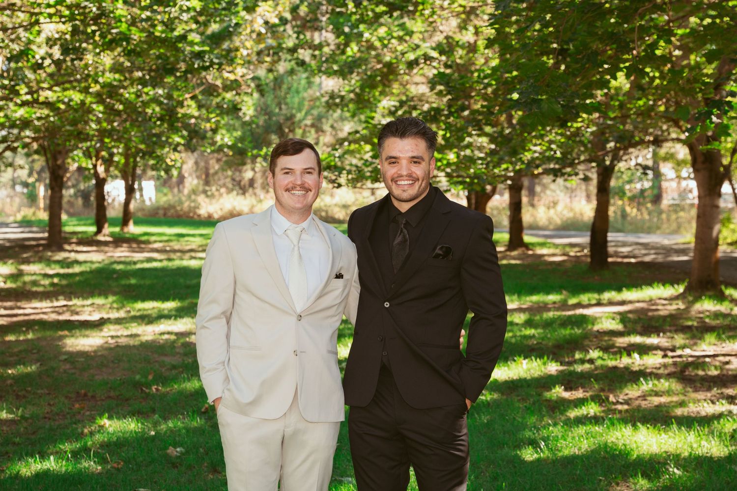 Wedding party members in light and dark formal attire posing outdoors.