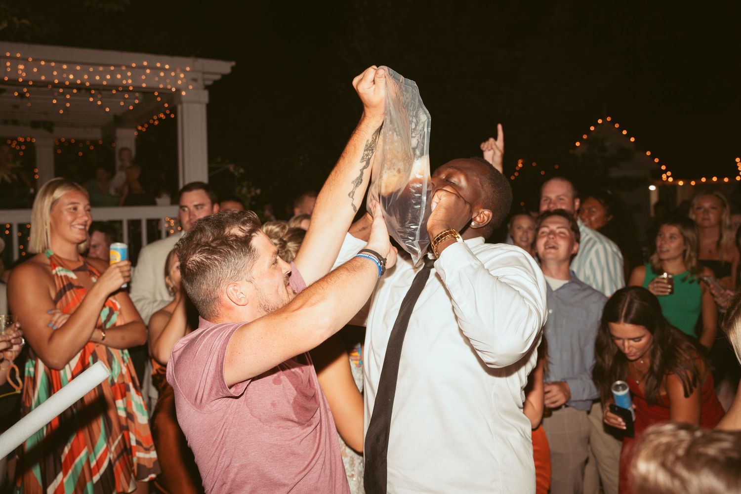 Guests enjoying themselves on a festive dance floor at an evening wedding celebration.