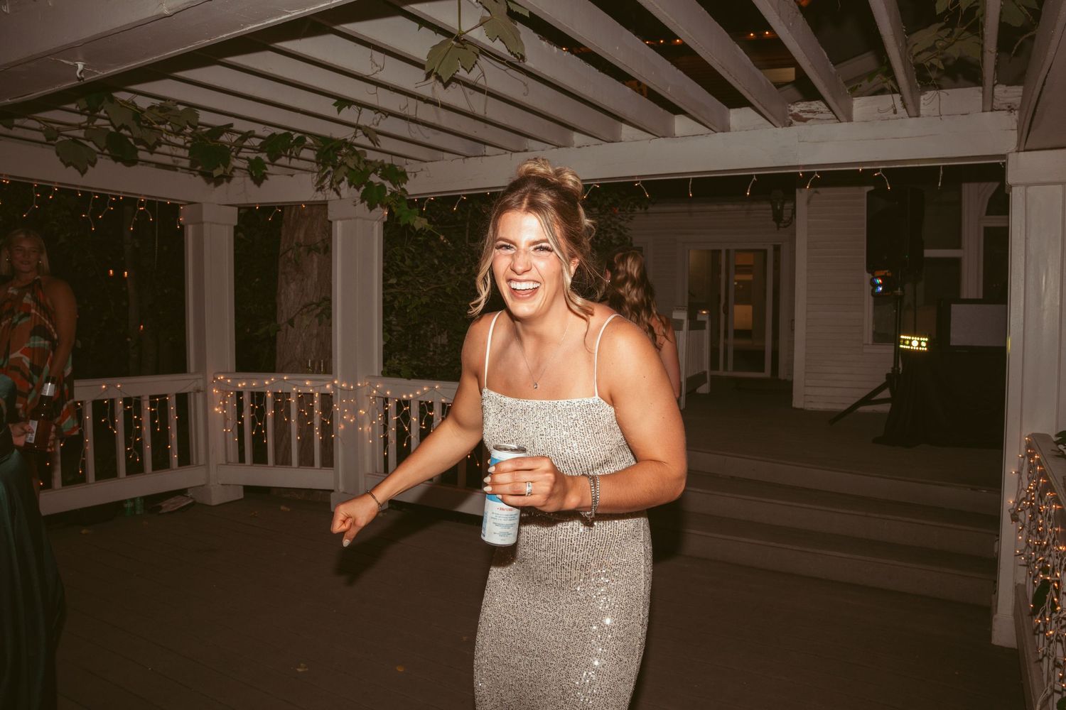 Person in sparkly dress dancing and celebrating at an indoor wedding reception venue.