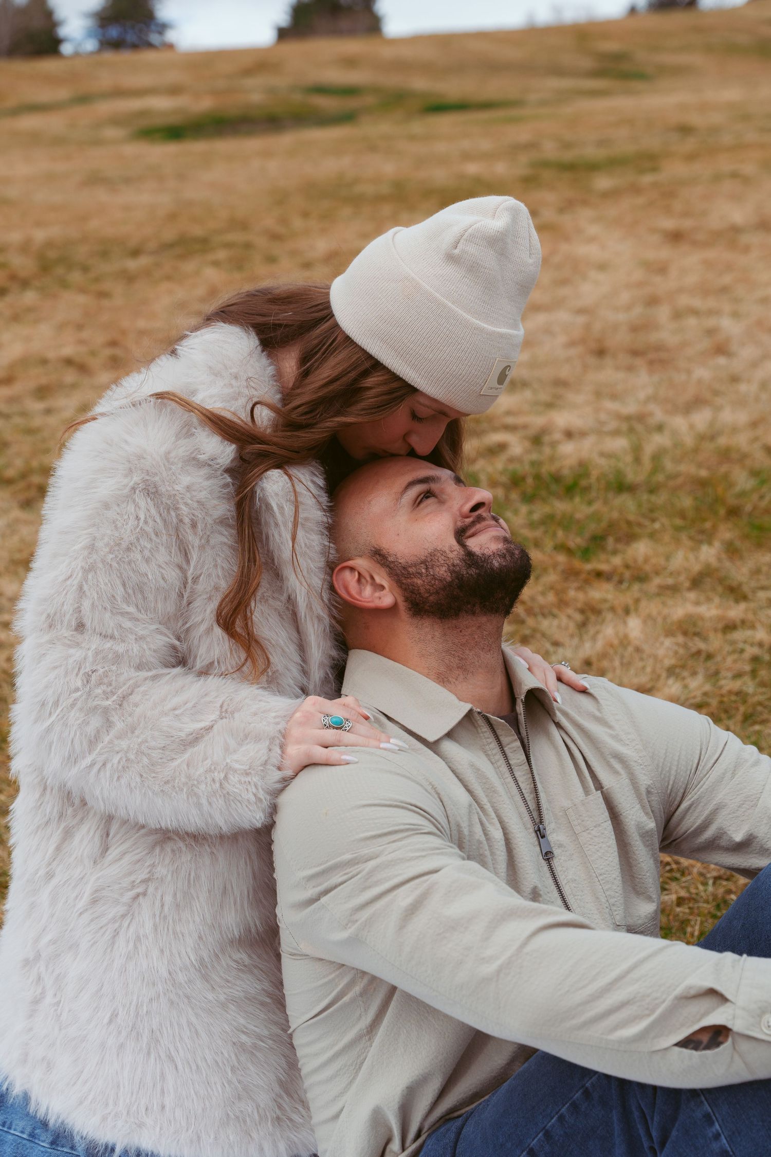Romantic outdoor photoshoot featuring couple in matching neutral tones against natural landscape.