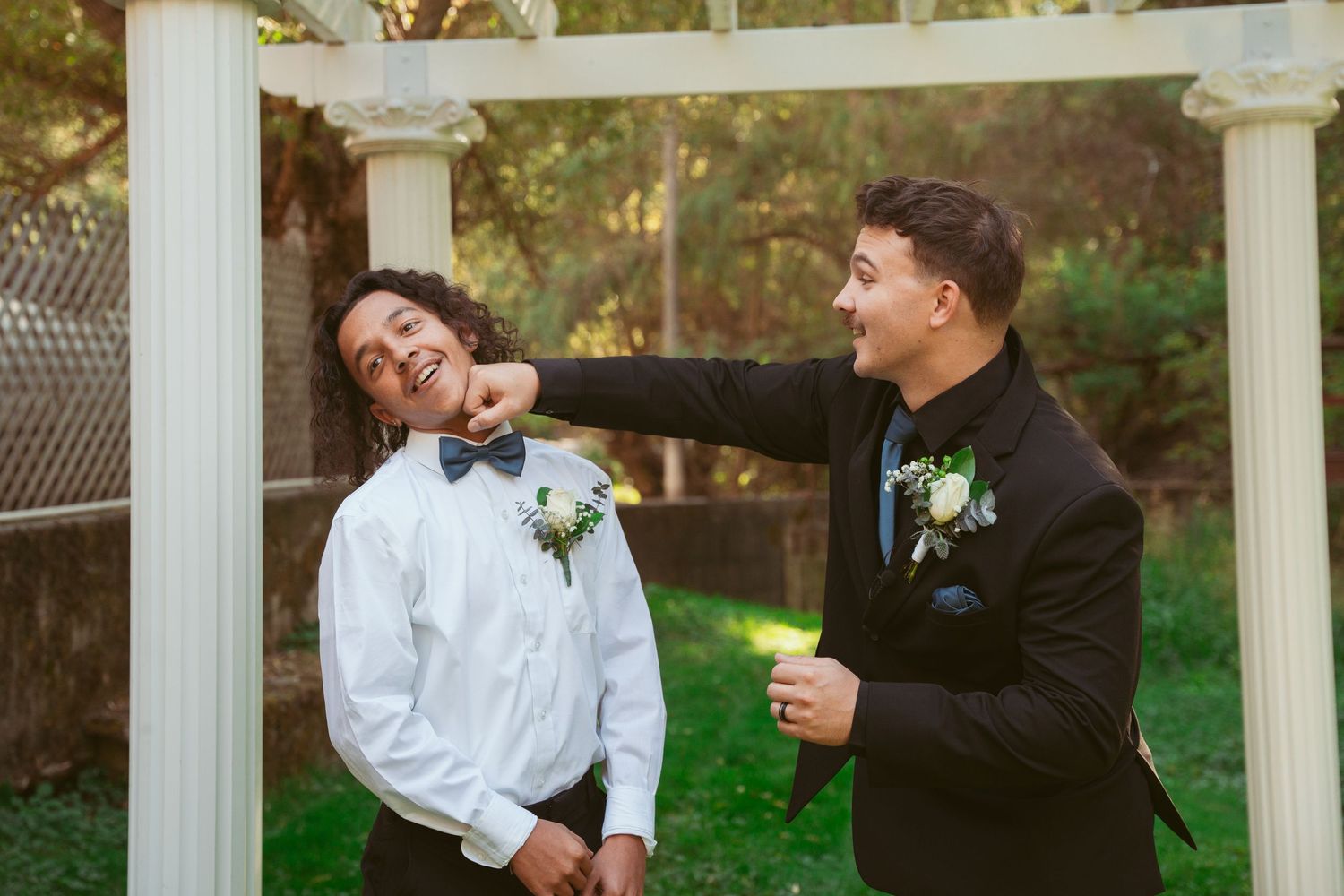 Playful moment captured under white garden pergola during wedding celebration.