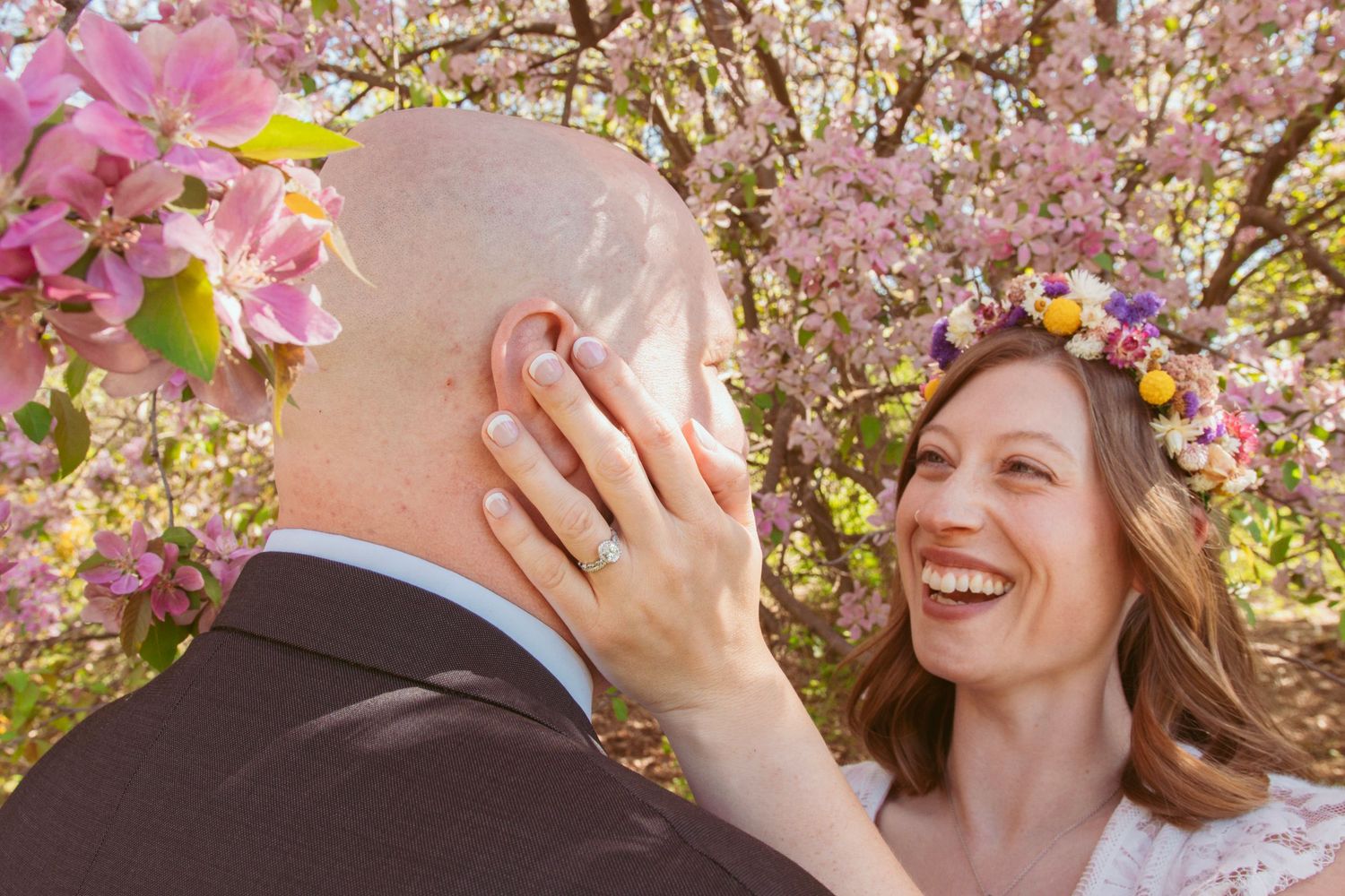 Cherry blossoms frame a romantic wedding moment under blooming spring trees.