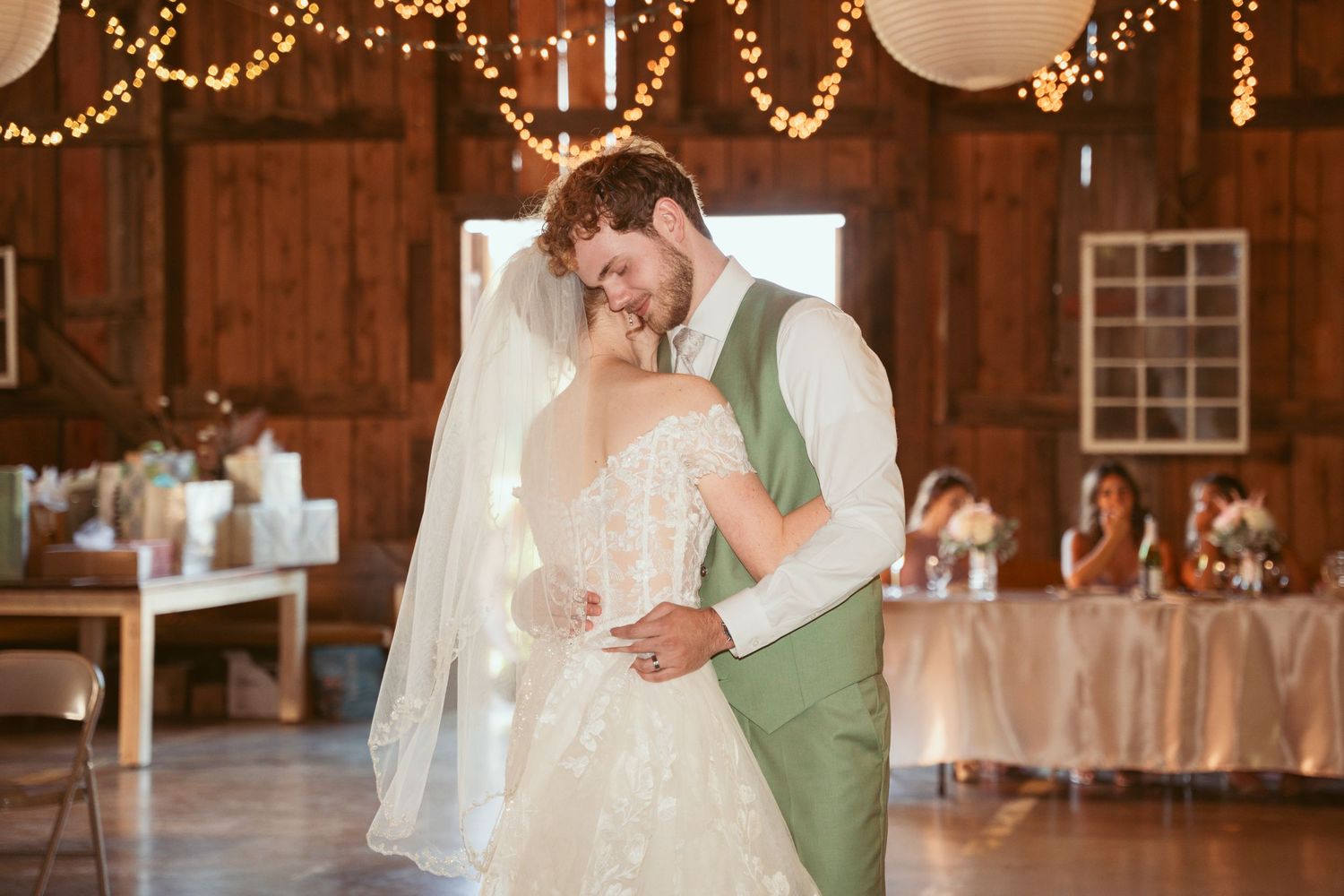 Couple sharing an intimate dance moment in a beautifully lit rustic barn venue.