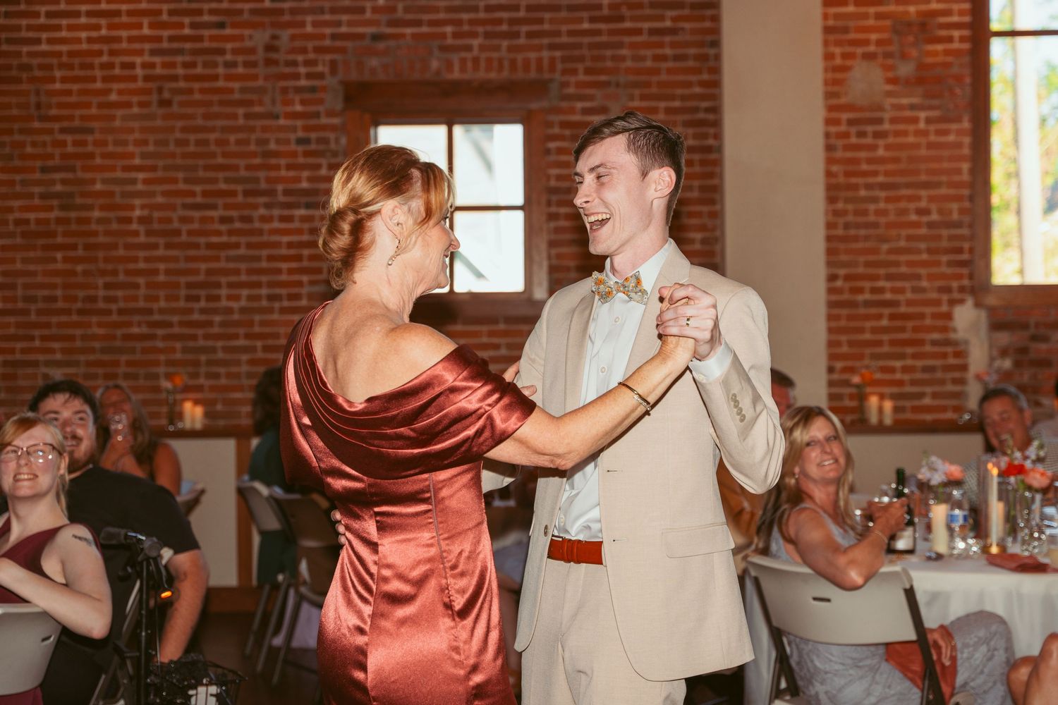 Couples dancing together at a wedding reception in a rustic brick venue.