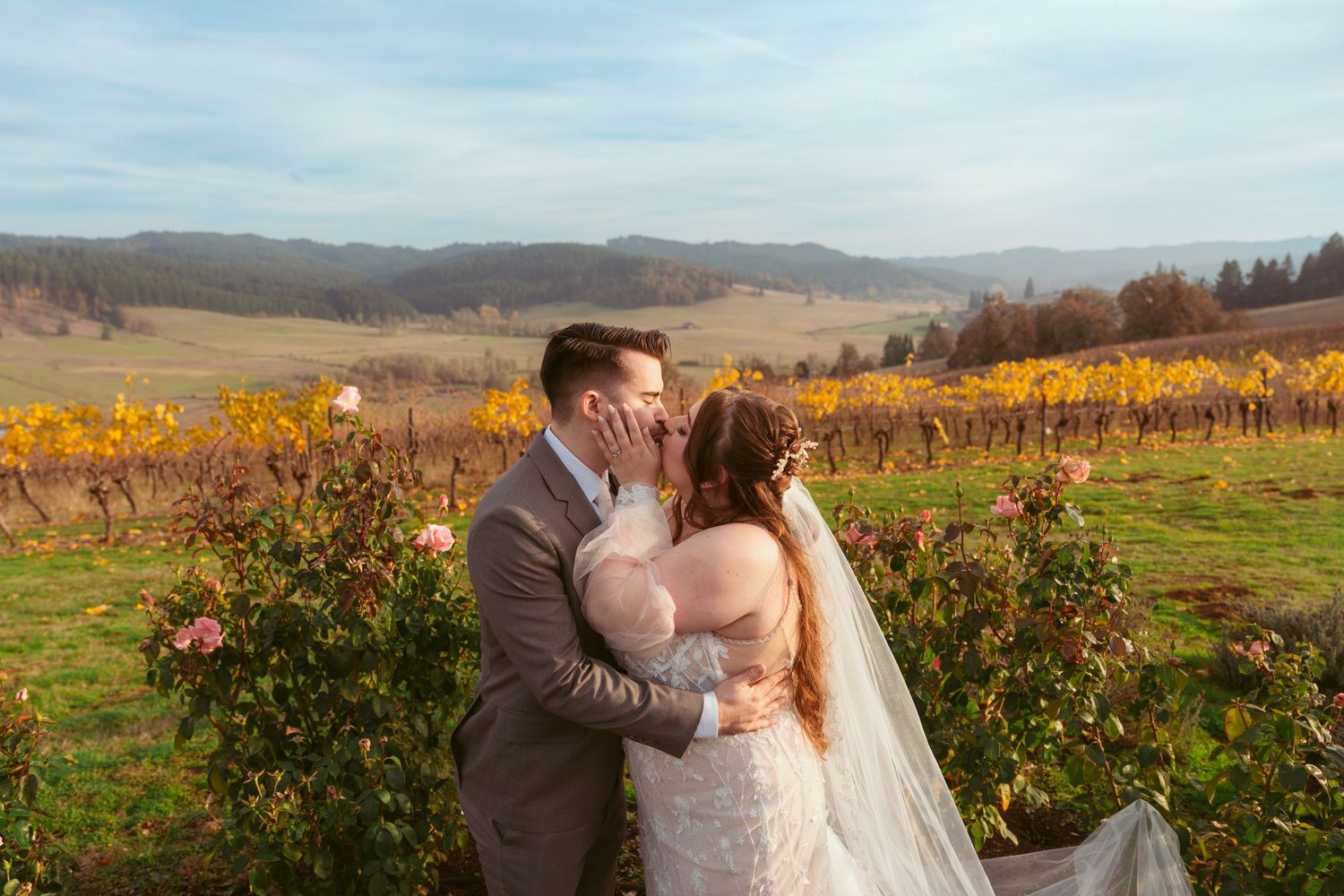 Wedding couple shares an intimate moment in a scenic vineyard with golden fall foliage.