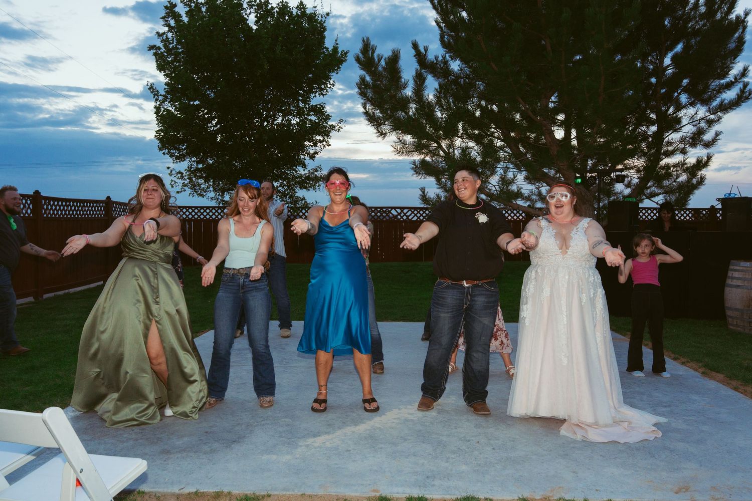 Wedding party performs choreographed dance moves on an outdoor patio.