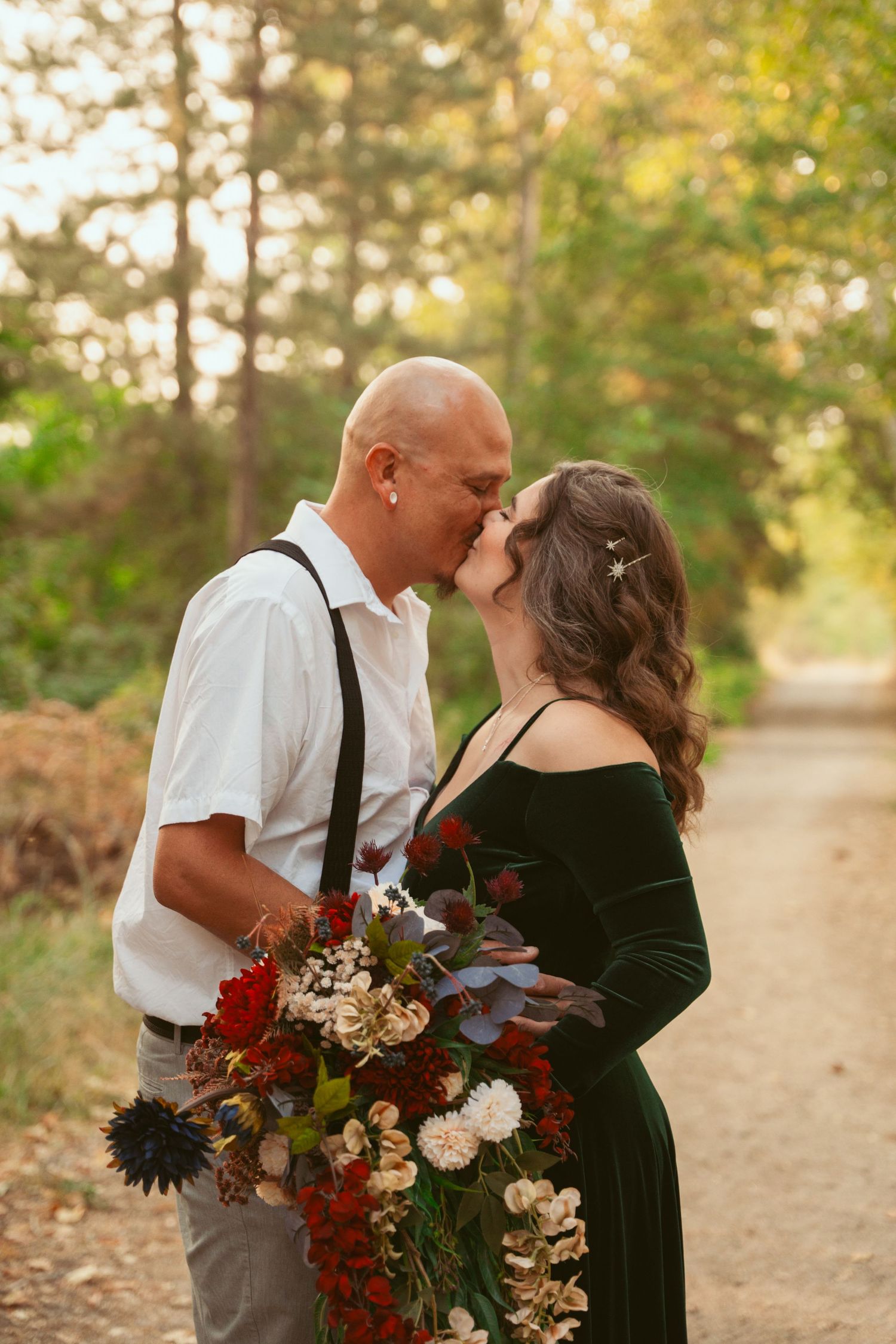 Romantic couple sharing a tender moment on a woodland path during golden hour.