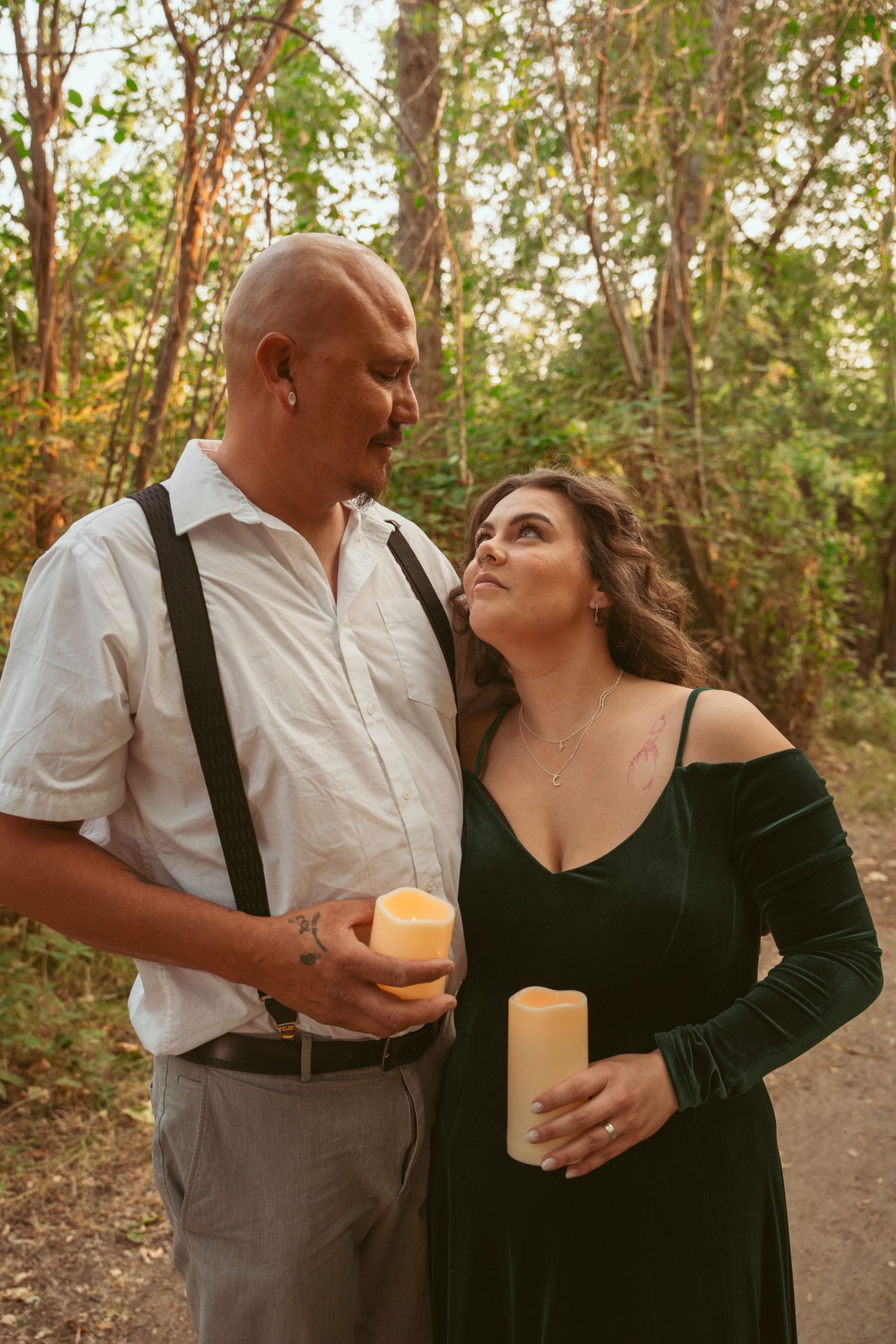 A couple in formal wear shares drinks and laughs during an outdoor photoshoot.