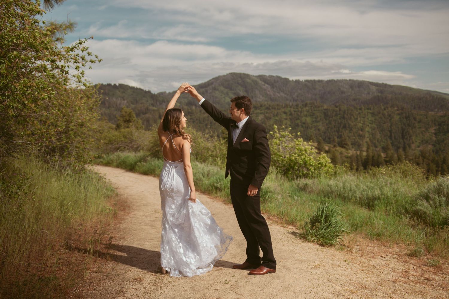 A couple performs a romantic dance sequence on a scenic mountain path surrounded by nature.