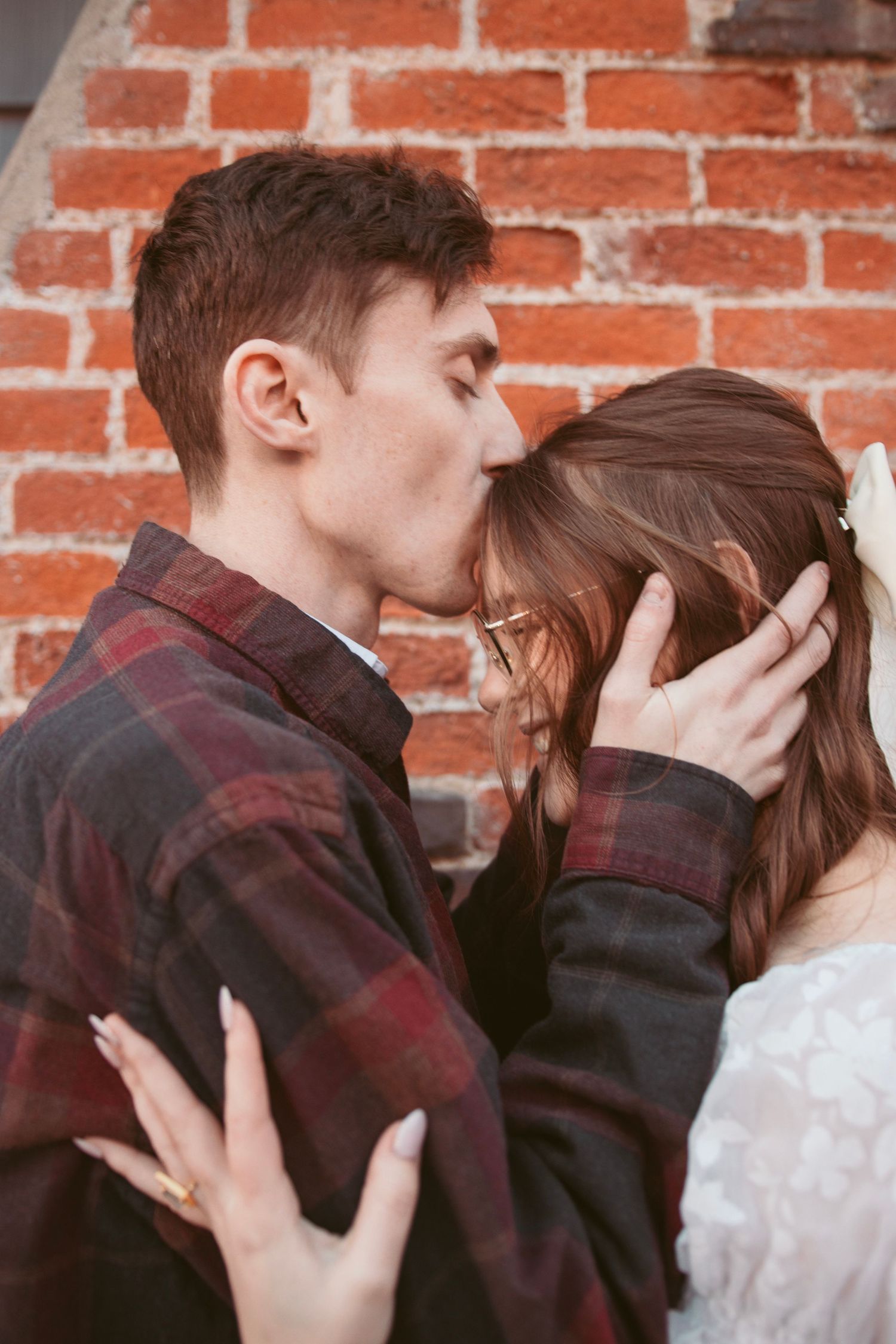 Romantic close-up moment against weathered brick wall background.