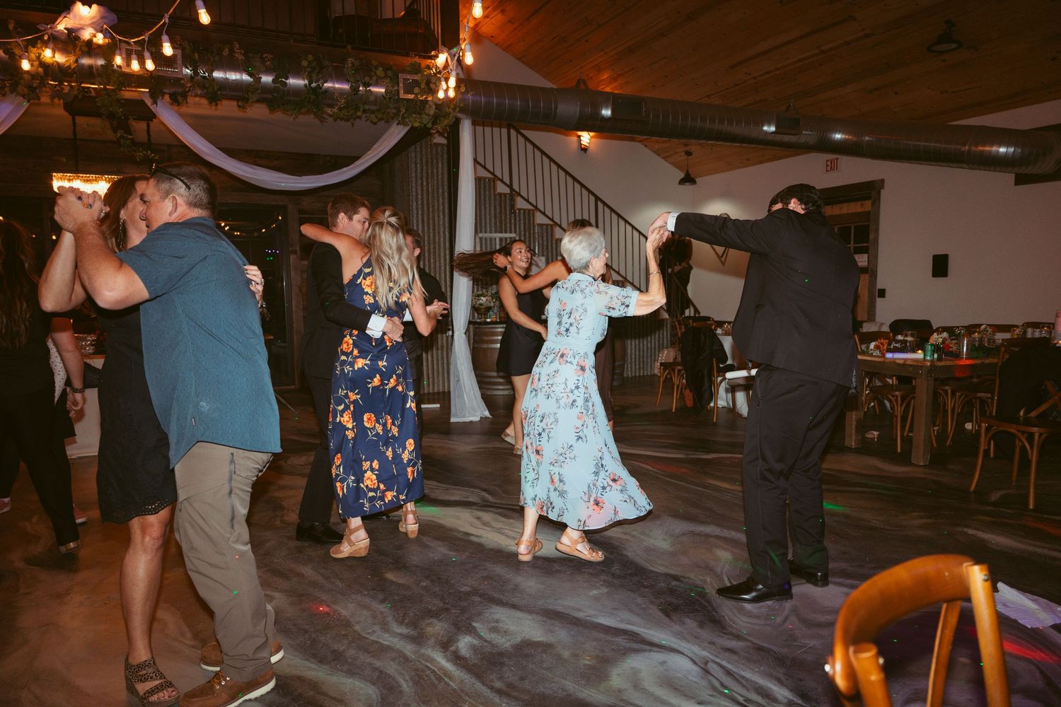 Couples enjoying partner dancing at an evening event with decorative overhead lighting.