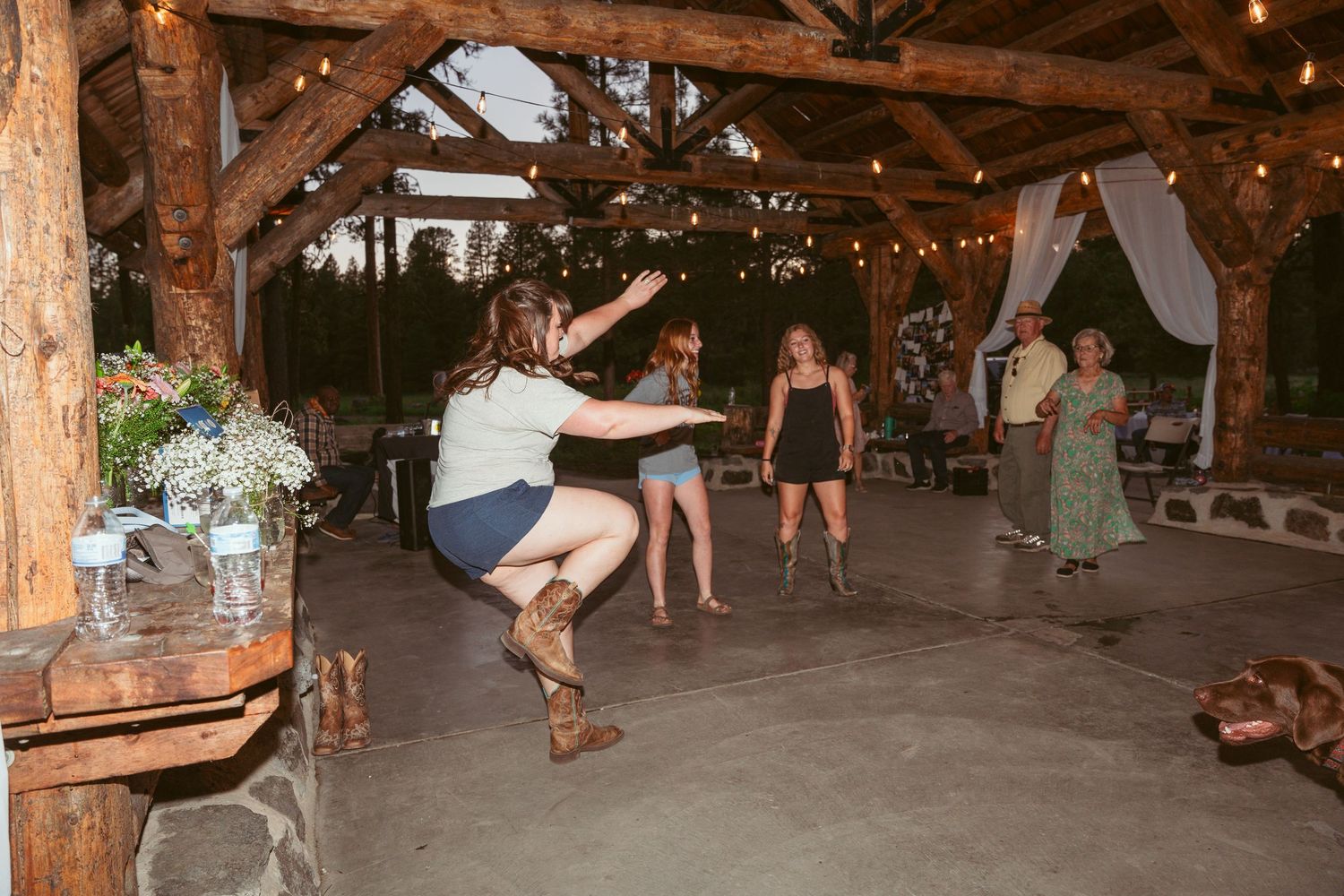 Guest showing off dance moves at rustic outdoor wedding reception.