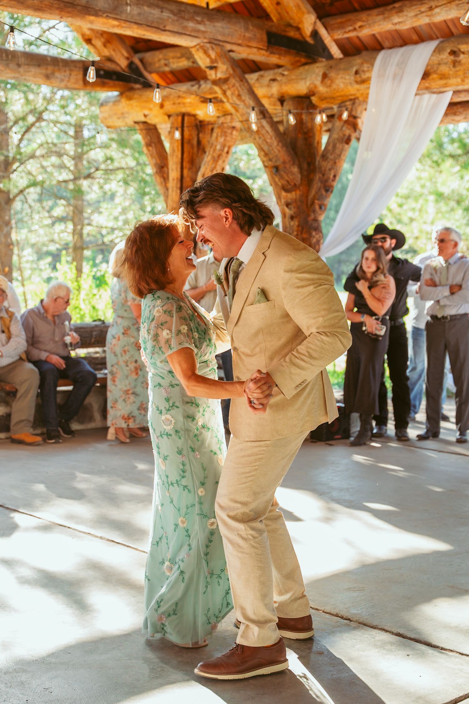 Couple performing a dance move under string lights at an outdoor wedding venue.