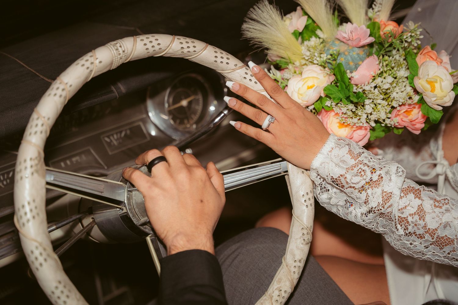 A decorative white floral wreath being assembled with hands placing flowers and greenery.