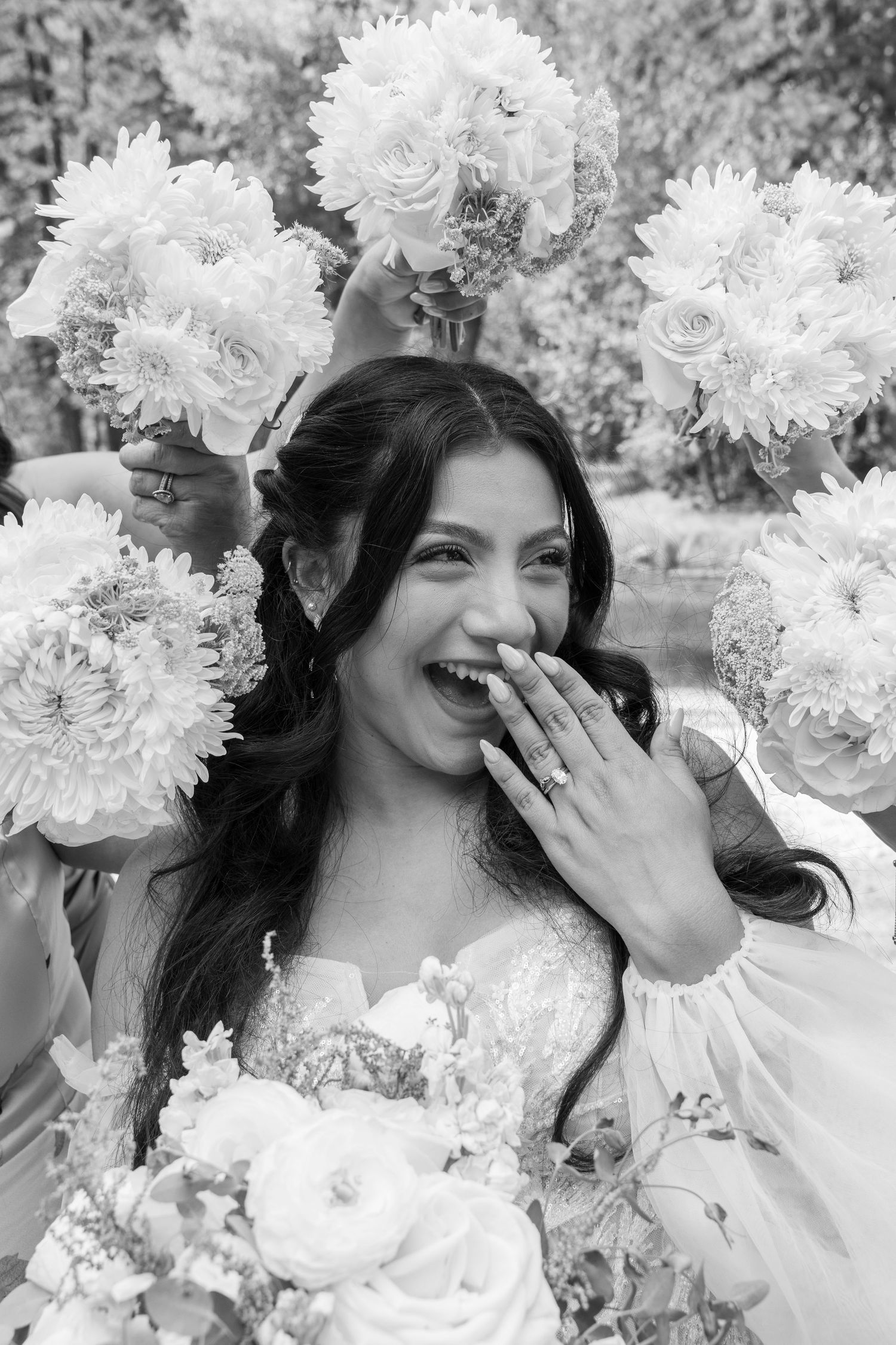 Black and white portrait of bride laughing with white dahlia bouquet.