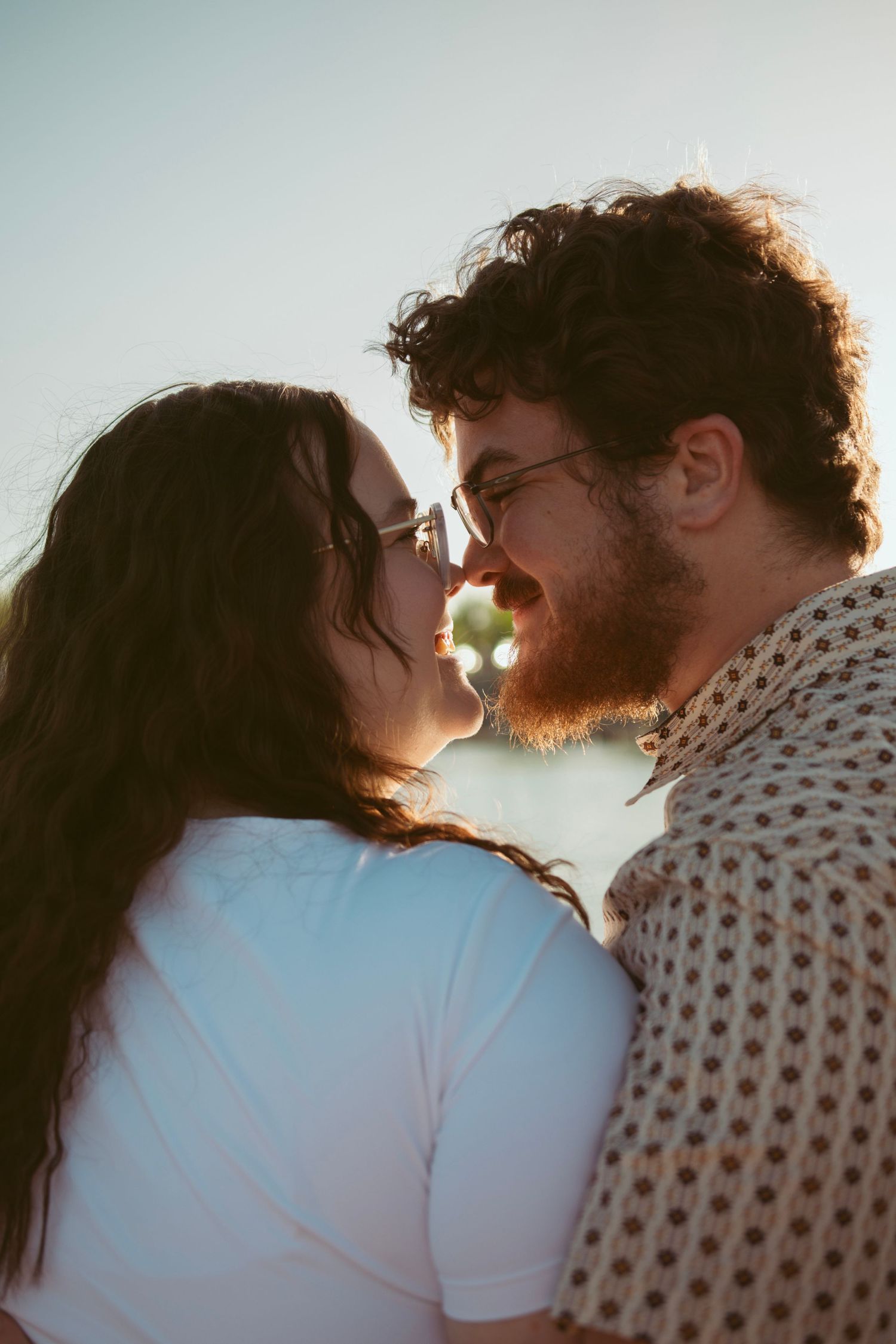 A romantic couple shares an intimate moment at sunset with soft lighting.