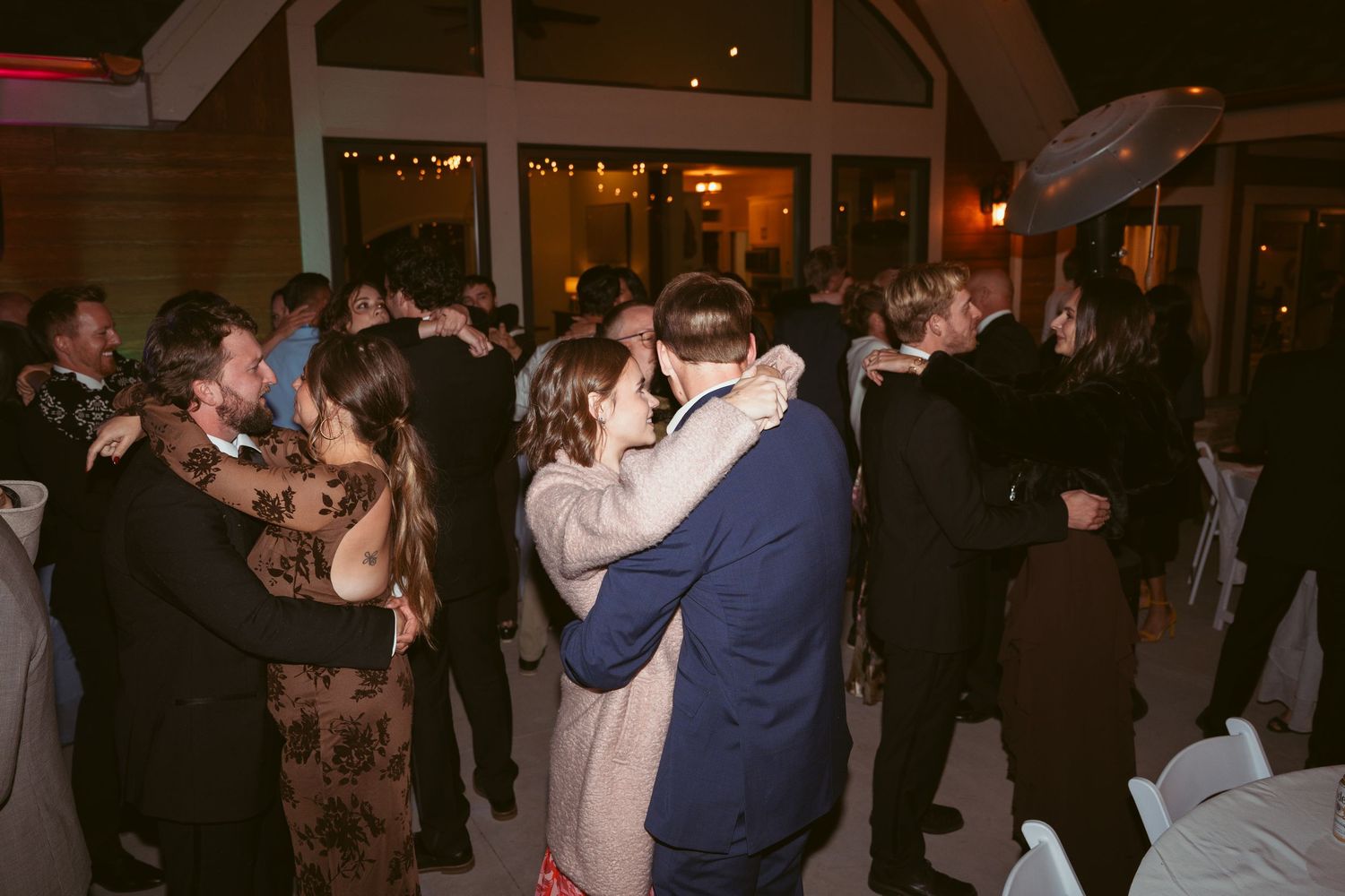 Wedding celebration with multiple couples dancing in an indoor venue.