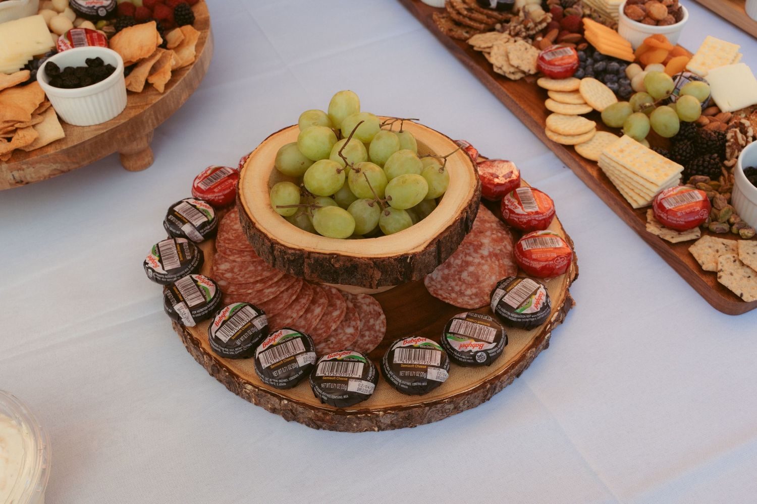 Rustic wood slice platters displaying assorted cheeses, grapes, and appetizers.