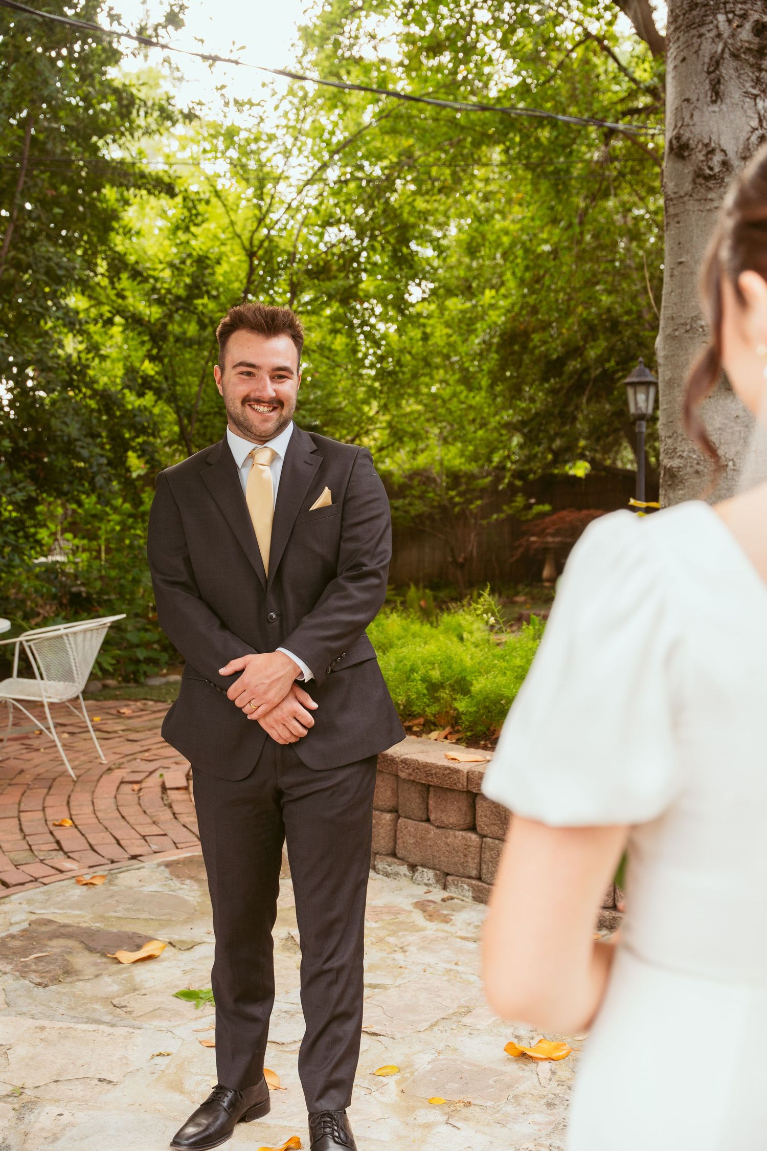 Wedding day first look sequence with groom in black suit waiting to see bride.