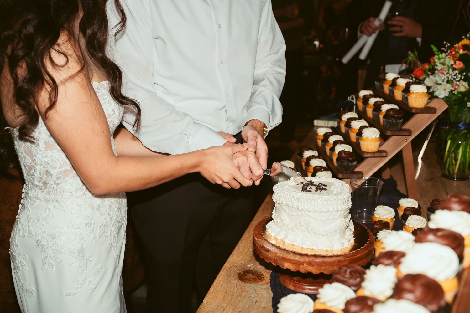 Close-up of elegant white wedding cake being cut during reception.