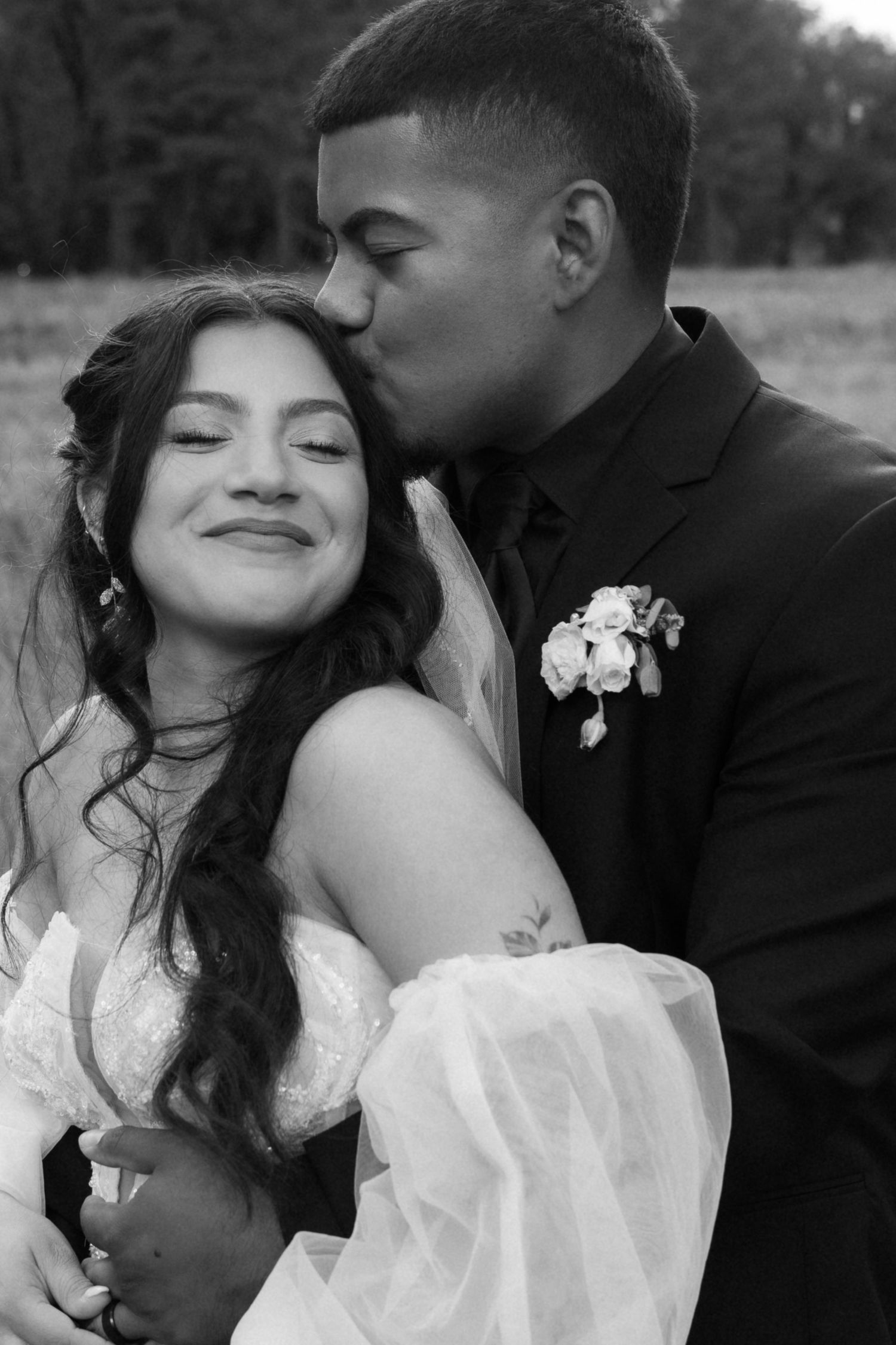 Intimate black and white wedding portrait showing tender moment between newlyweds.