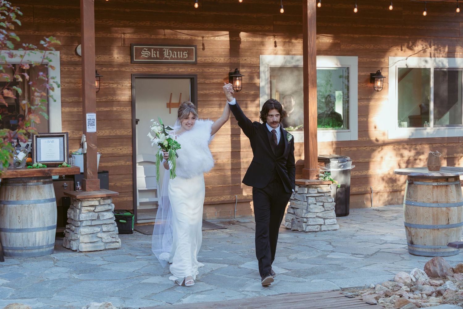 Rustic wood-paneled wedding venue with string lights and stone pillars.