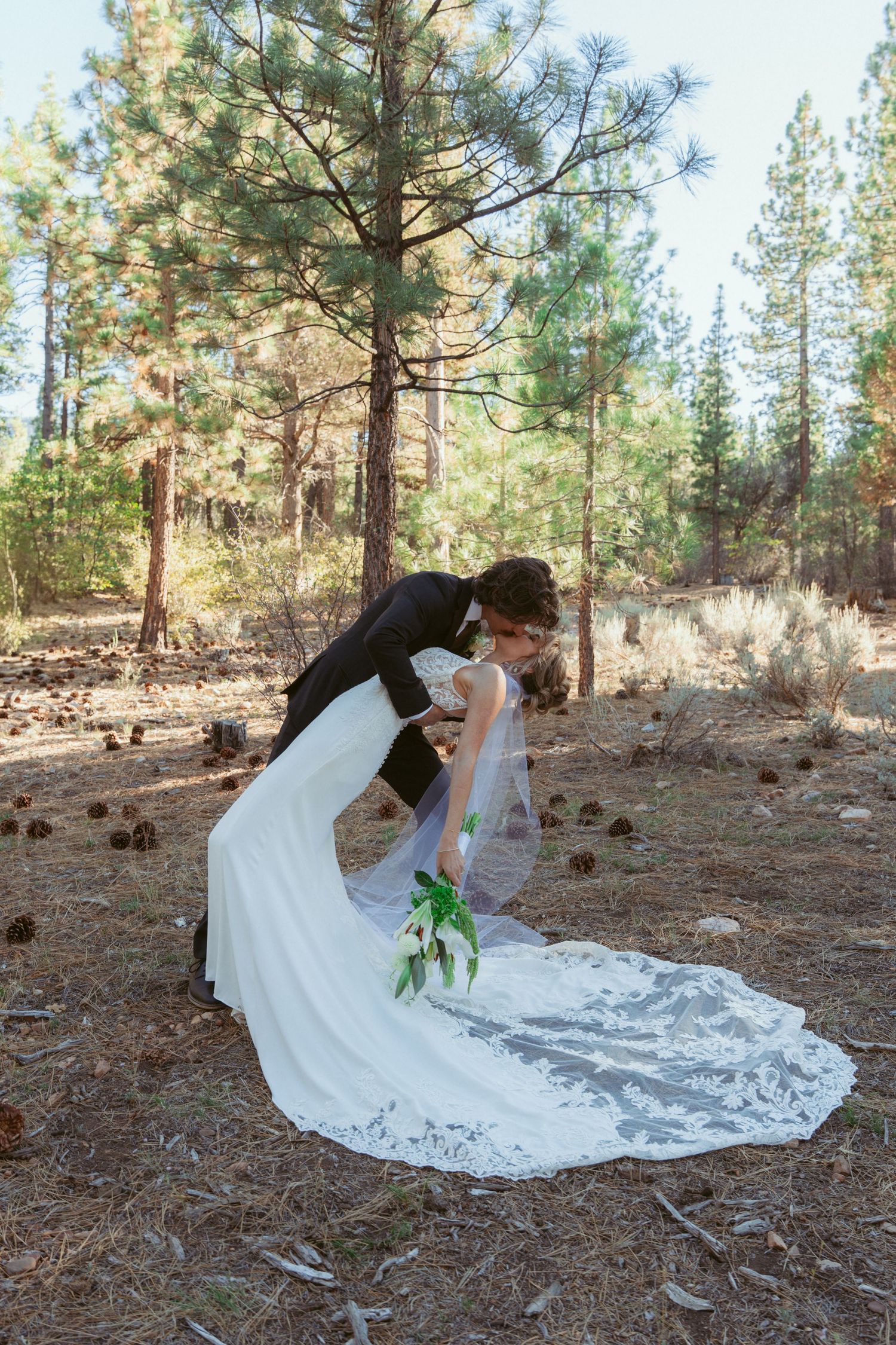 A dramatic dip pose sequence during a forest wedding photoshoot with a flowing white dress.