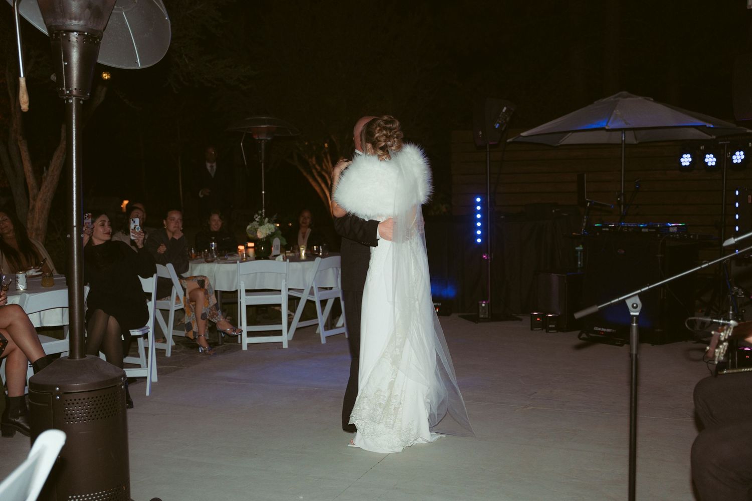 Evening wedding reception with blue lighting and white outdoor furniture setup.