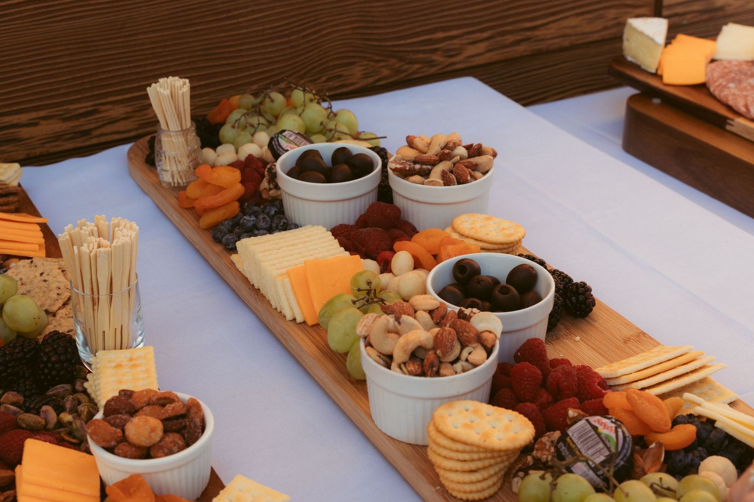 Charcuterie board spread with various meats, cheeses, fruits, and nuts arranged on a wooden surface.
