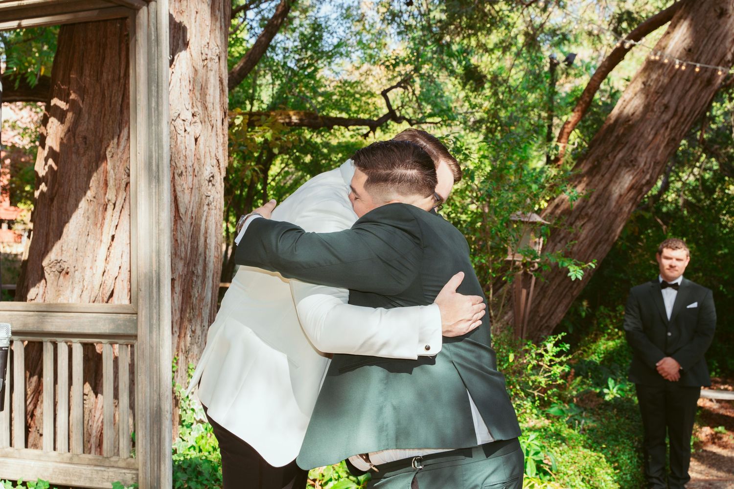 Wedding couple shares intimate moments under wooden pergola surrounded by greenery.