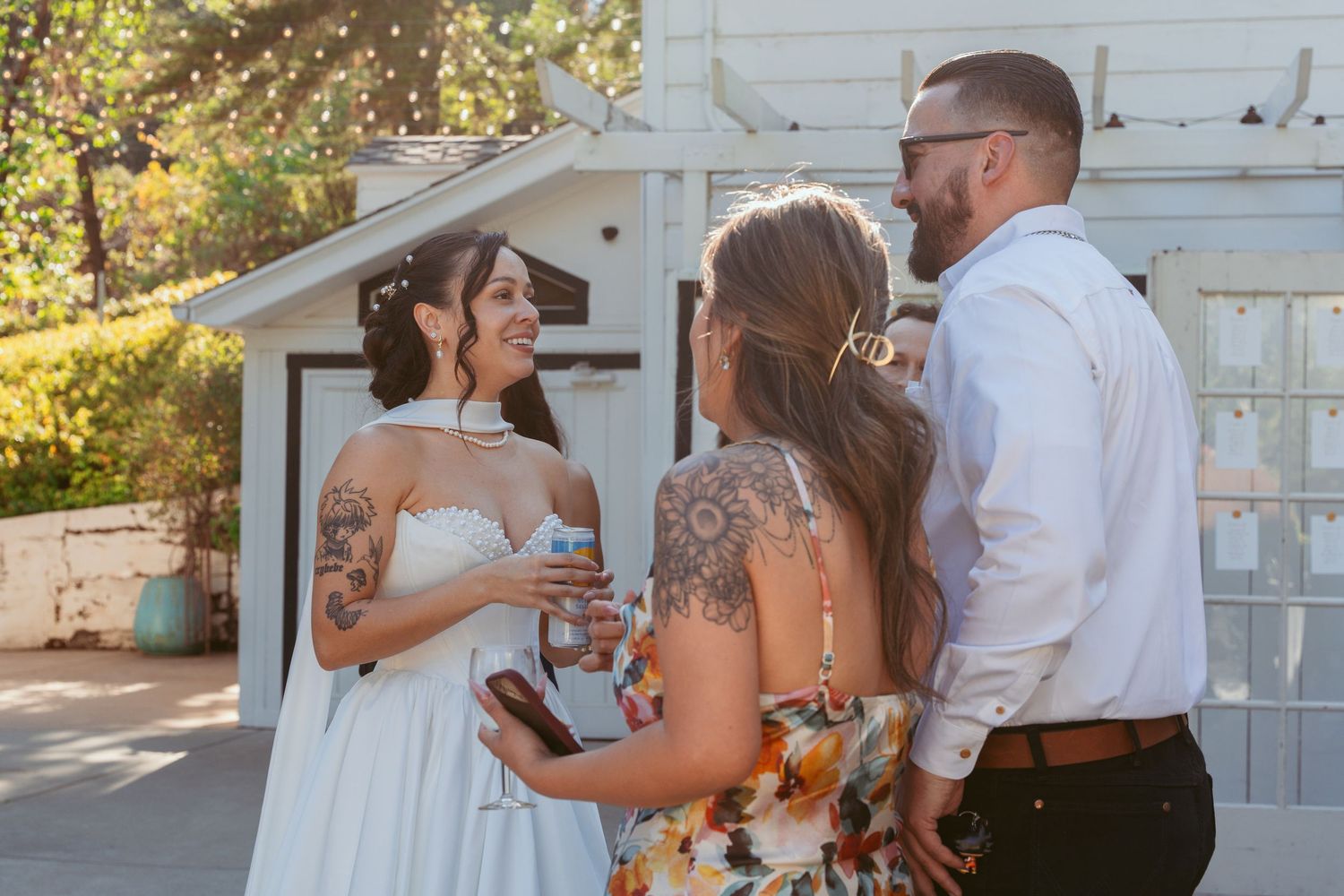 Wedding guests chatting and holding drinks during an outdoor daytime reception.