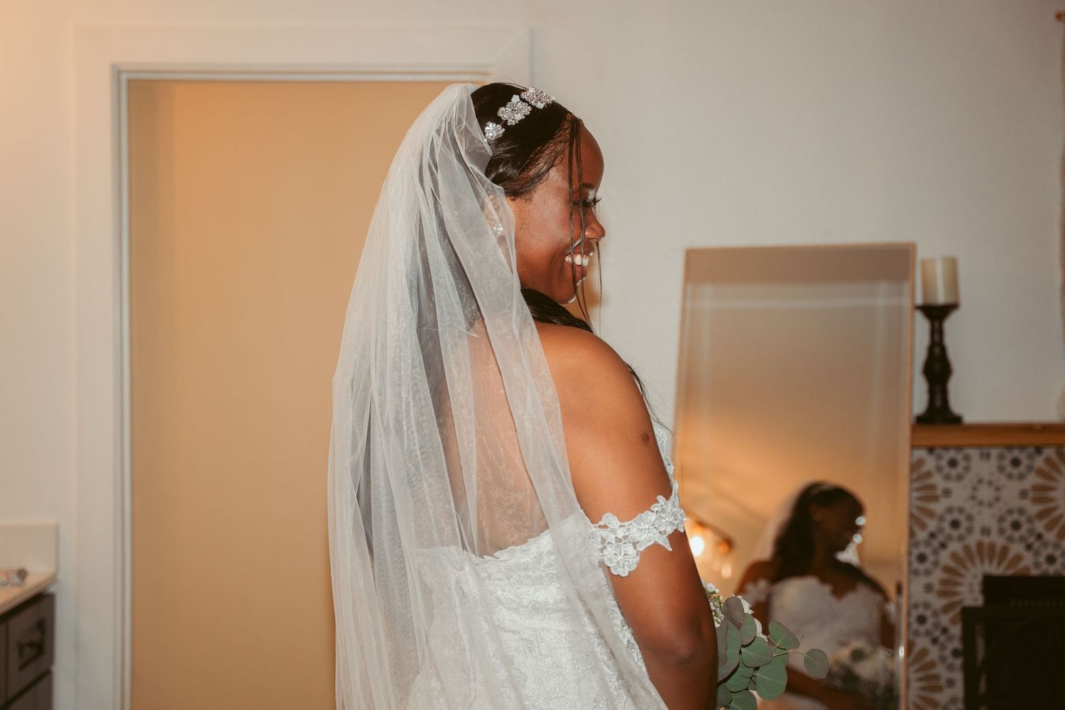 A bride in a white lace dress prepares for her wedding day indoors.