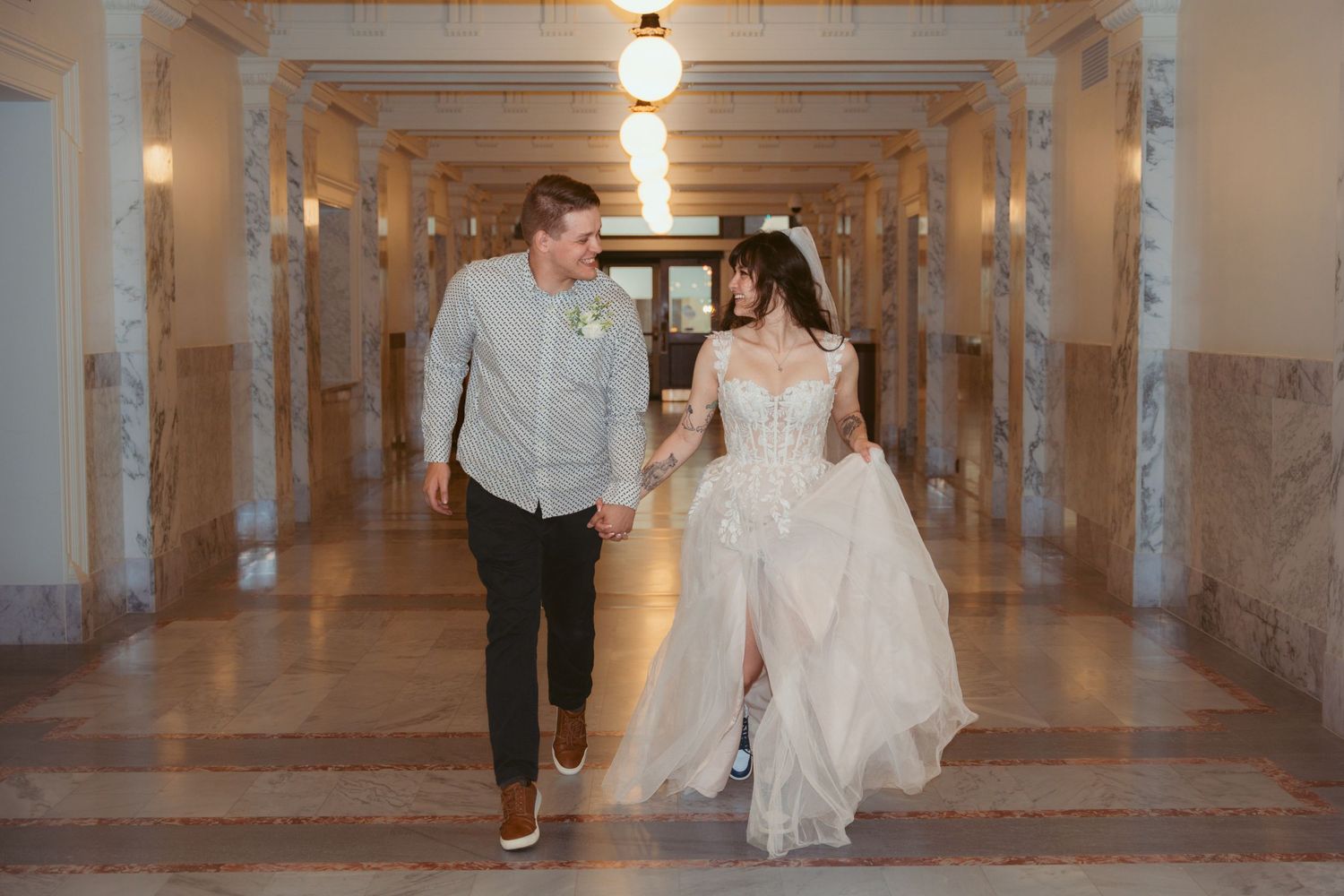 A couple walks together through a marble hallway with elegant lighting.