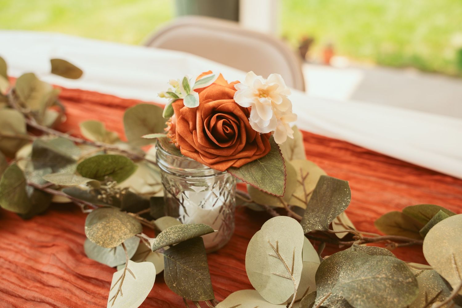 Red roses and greenery decorations arranged on a rustic surface.