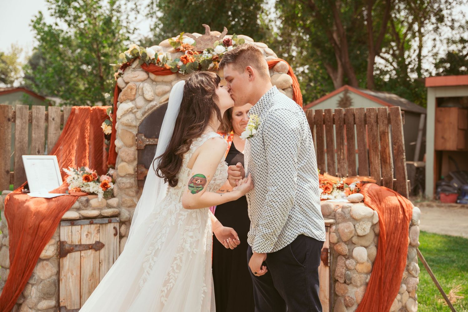 A couple shares an intimate outdoor moment surrounded by autumn foliage and rustic decor.