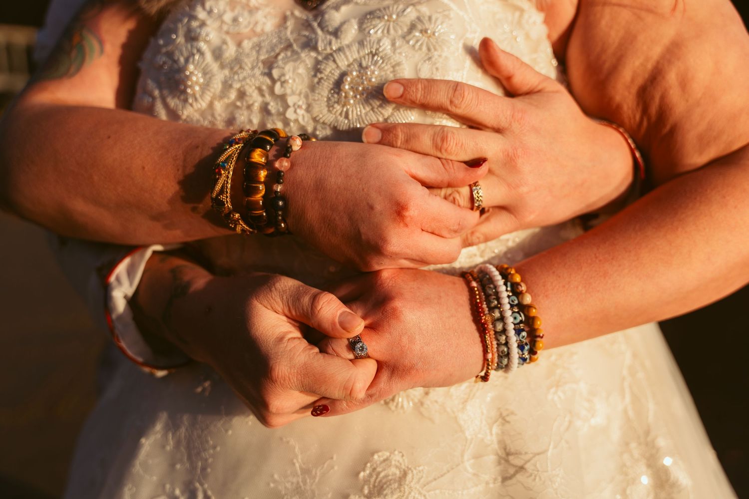 Detailed view of hands with jewelry against intricate white lace fabric.