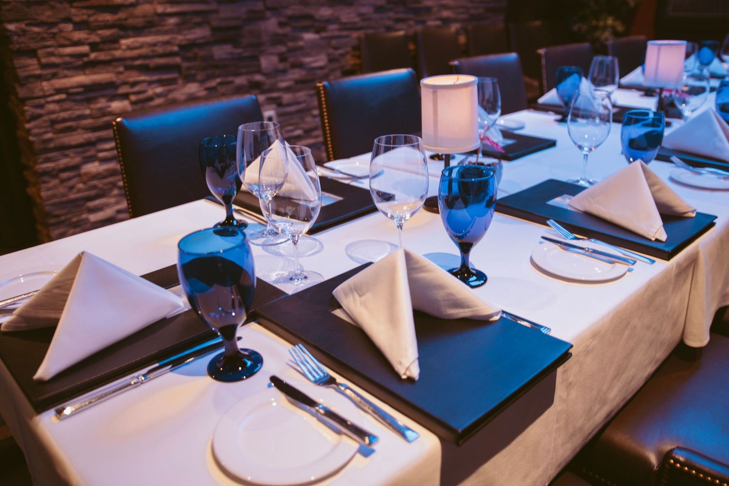 Elegant table settings with white napkins and wine glasses at a formal dining event.