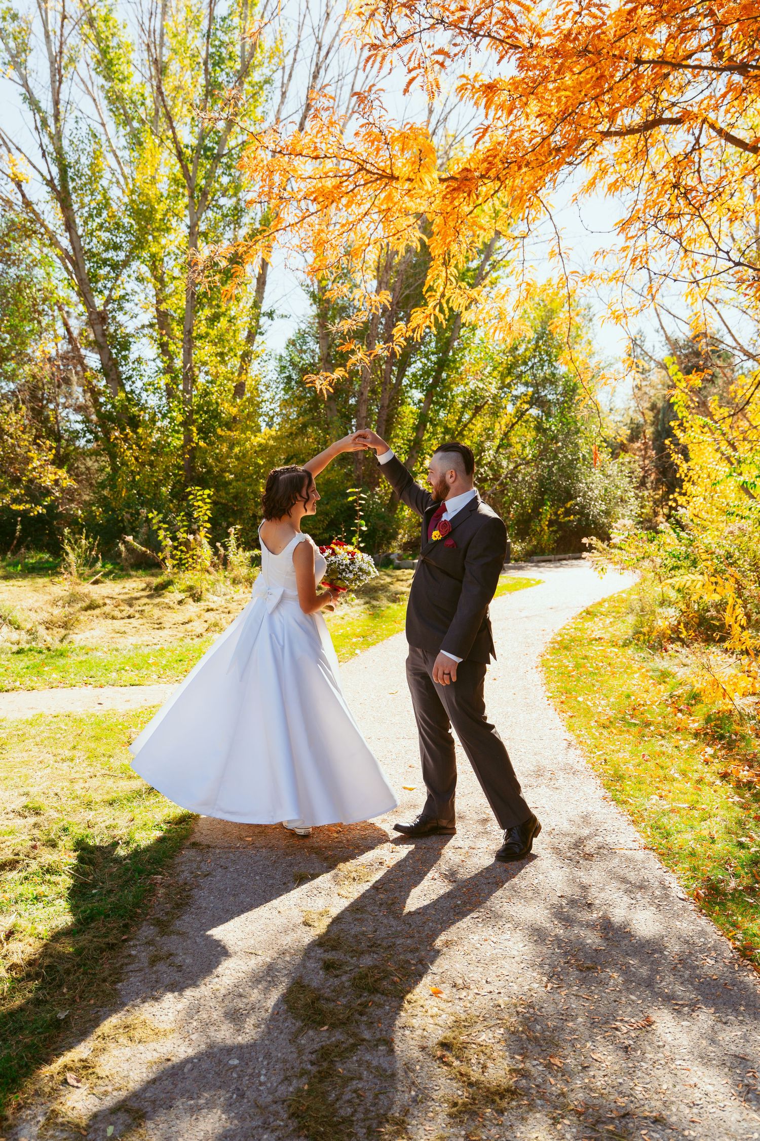 A couple shares playful moments while walking on a sun-dappled autumn trail.