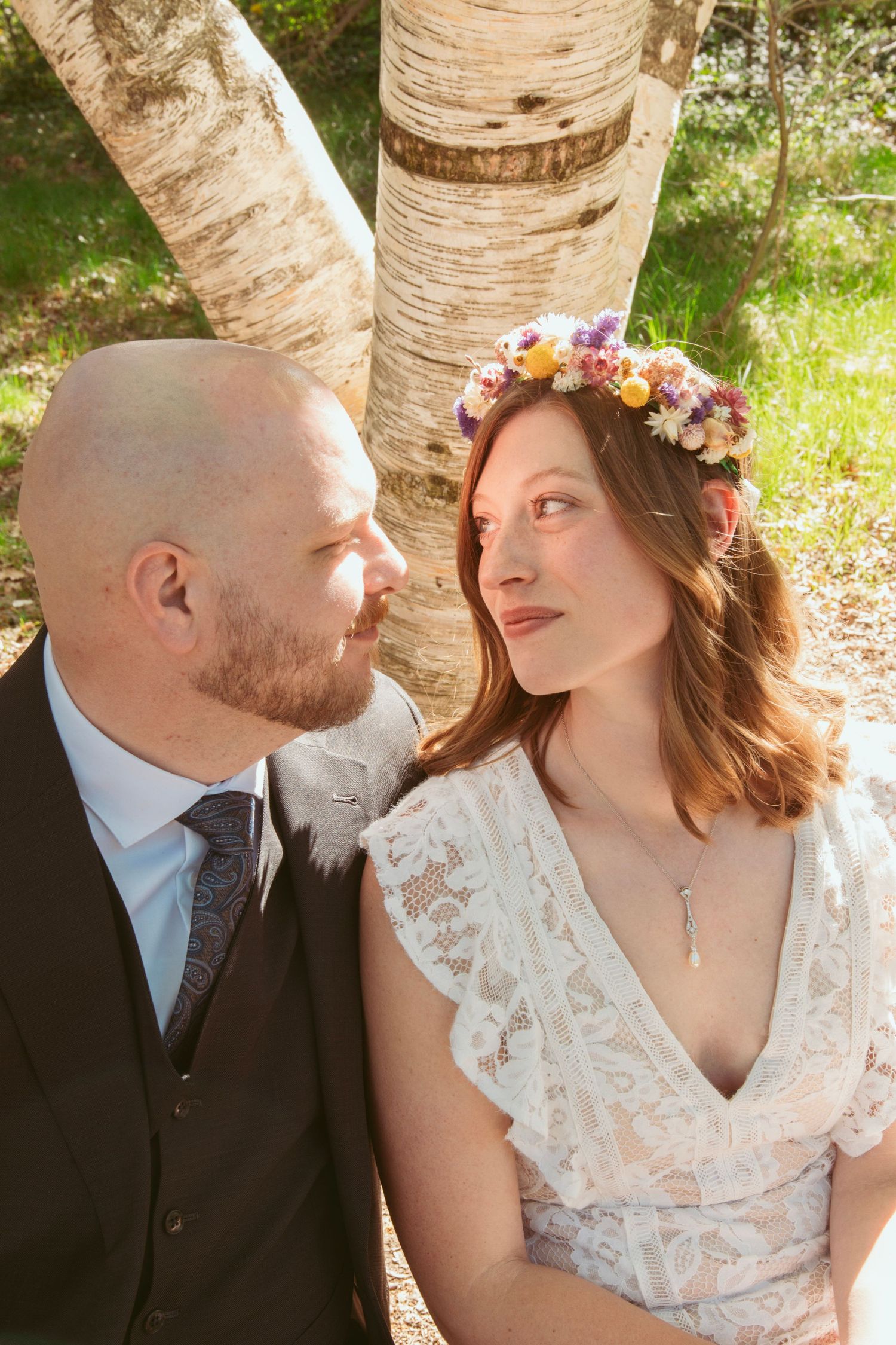 A romantic portrait session against birch trees with the bride wearing a floral crown and lace dress.
