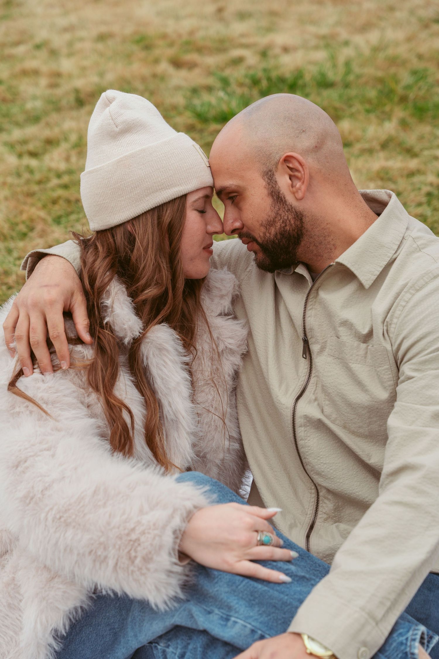 Couple in white and beige outfits sharing tender moments during outdoor photoshoot.