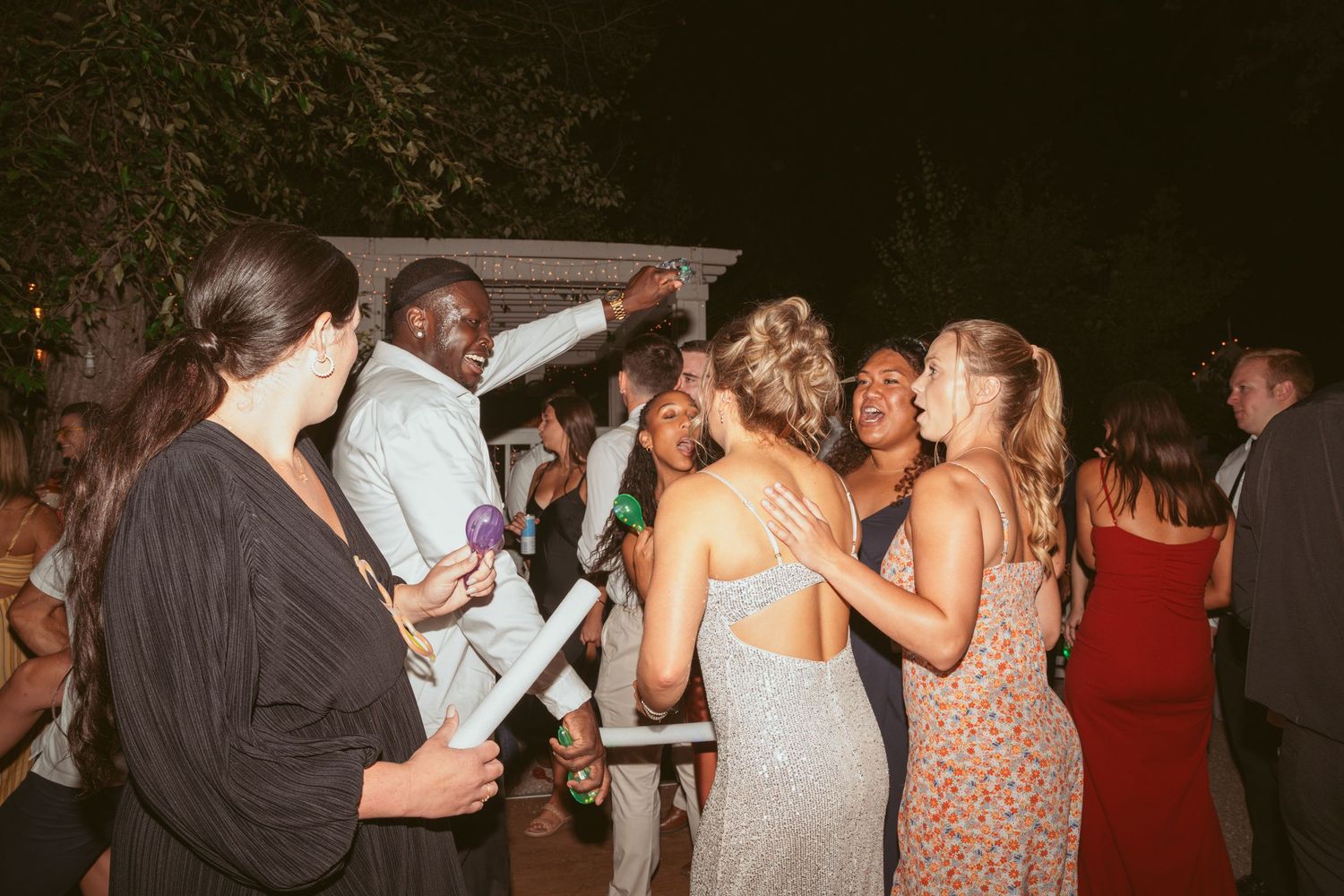 Guests enjoying themselves on the dance floor at a nighttime wedding celebration.