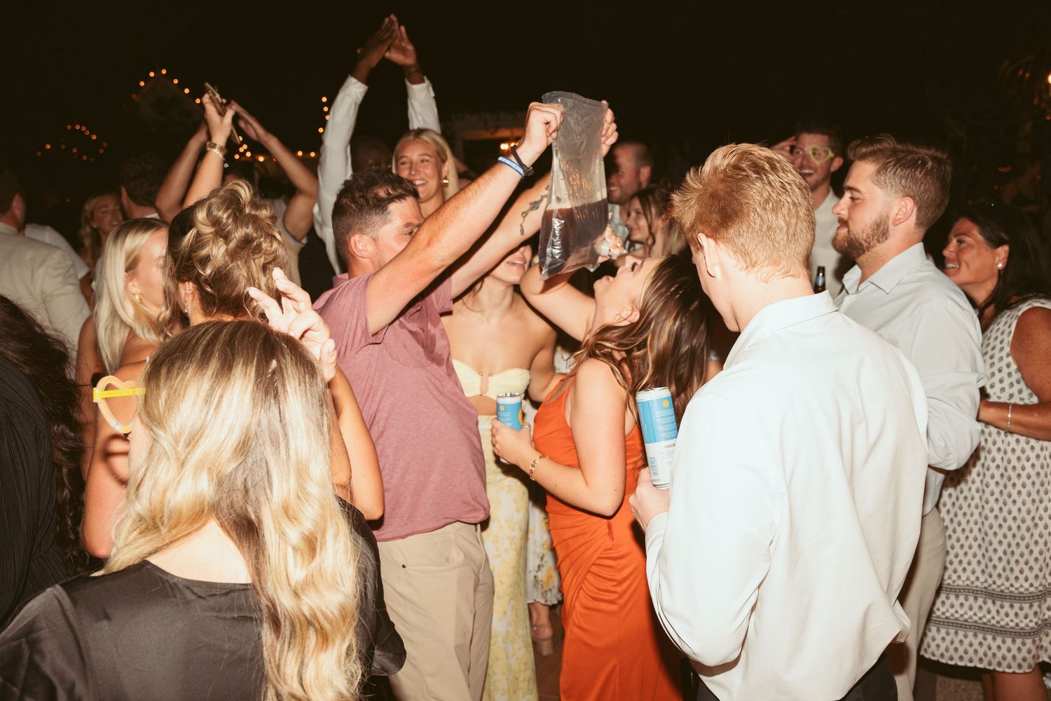 Guests celebrate on a dimly lit dance floor during an evening wedding reception.