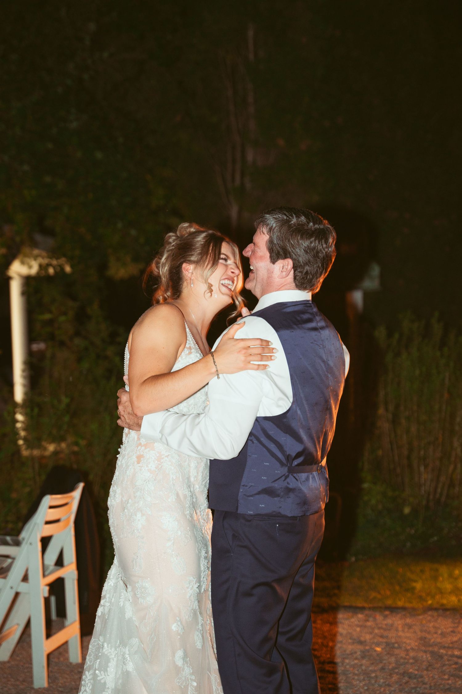 Couple sharing an intimate dance moment under twinkling lights at an outdoor wedding.