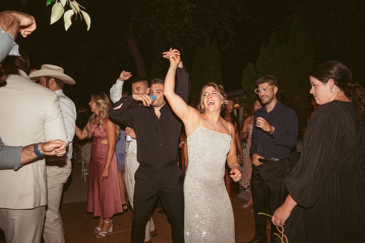 Wedding celebration on dance floor with guests enjoying the festivities at night.