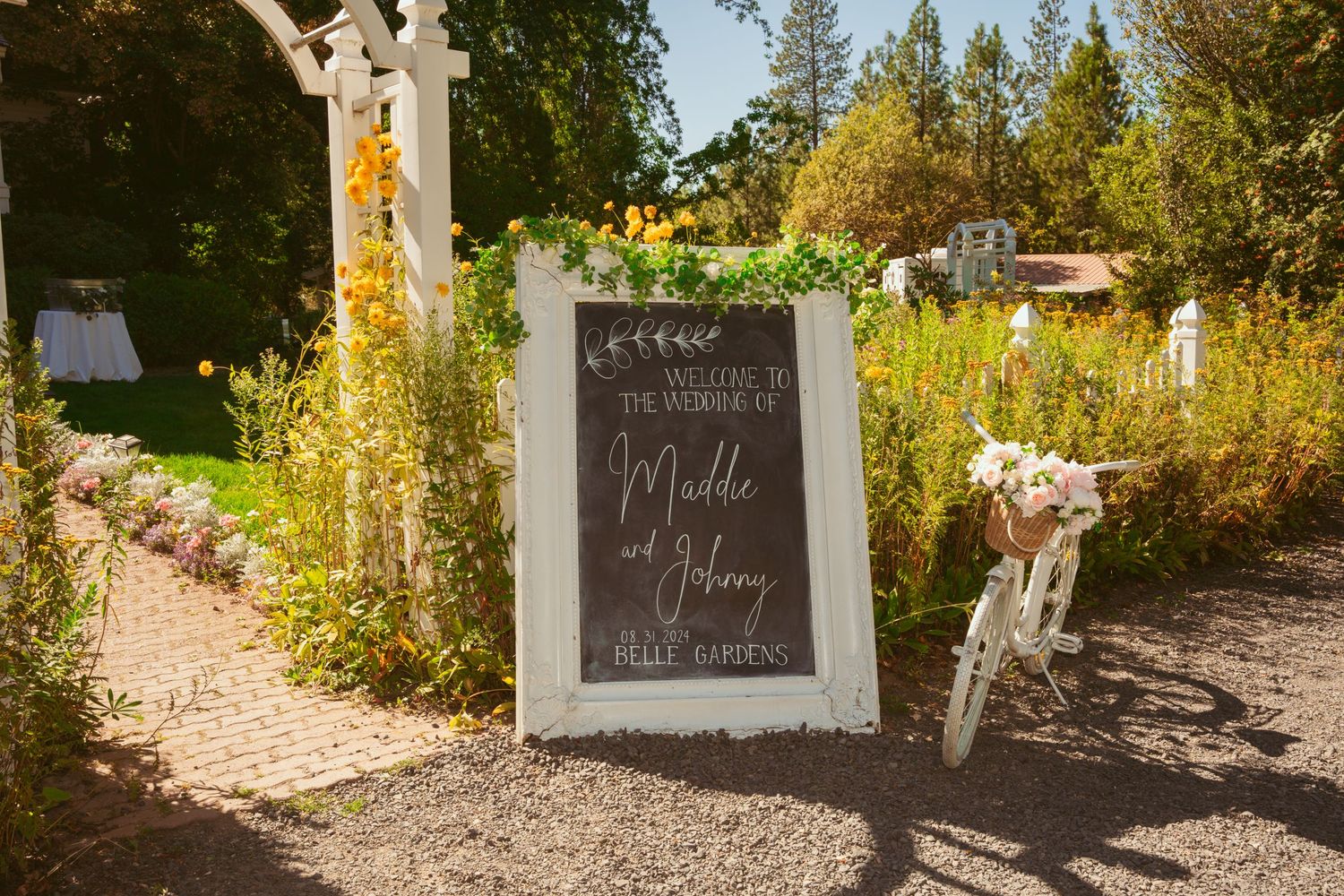 Rustic outdoor wedding venue pathway lined with trees and decorated with chalkboard signs.
