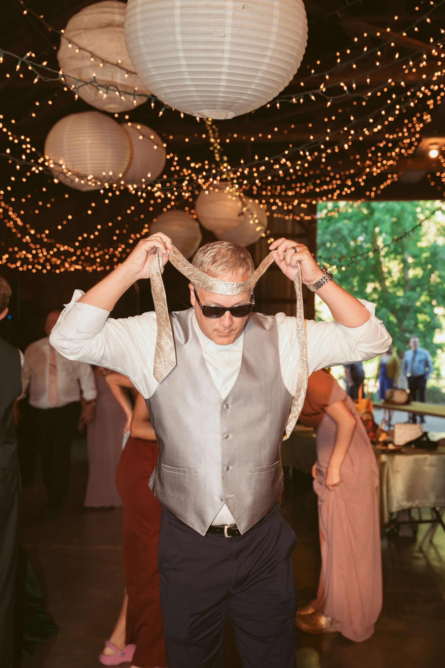 Wedding guests dancing energetically under a ceiling of fairy lights and paper lanterns.